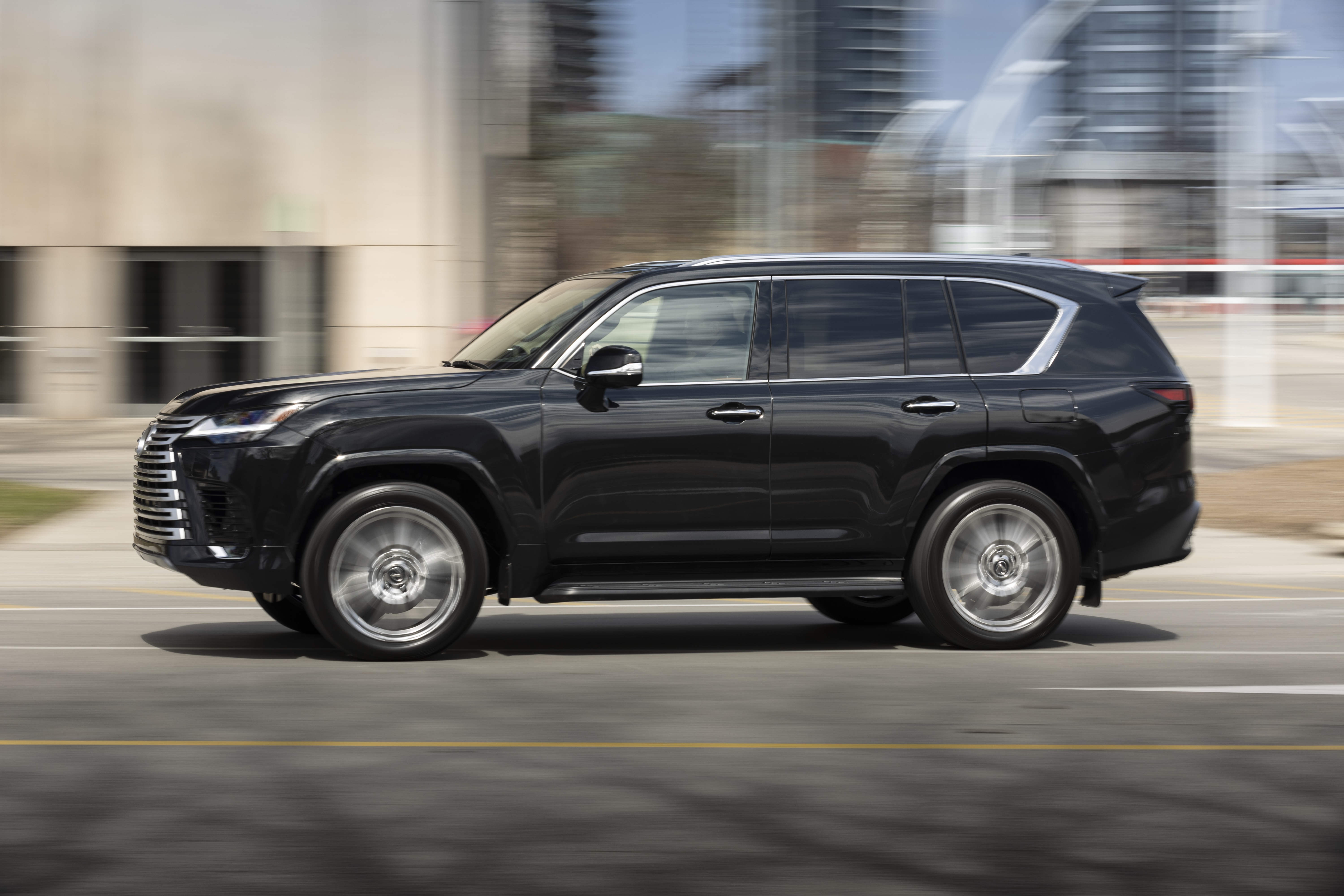 Black Lexus LX 600 driving on a city street HD Wallpaper