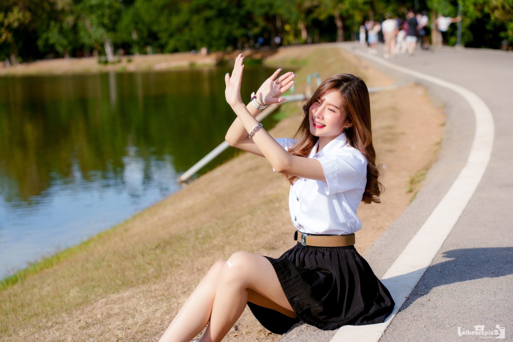 Asian woman in uniform sitting by a park lake HD Wallpaper