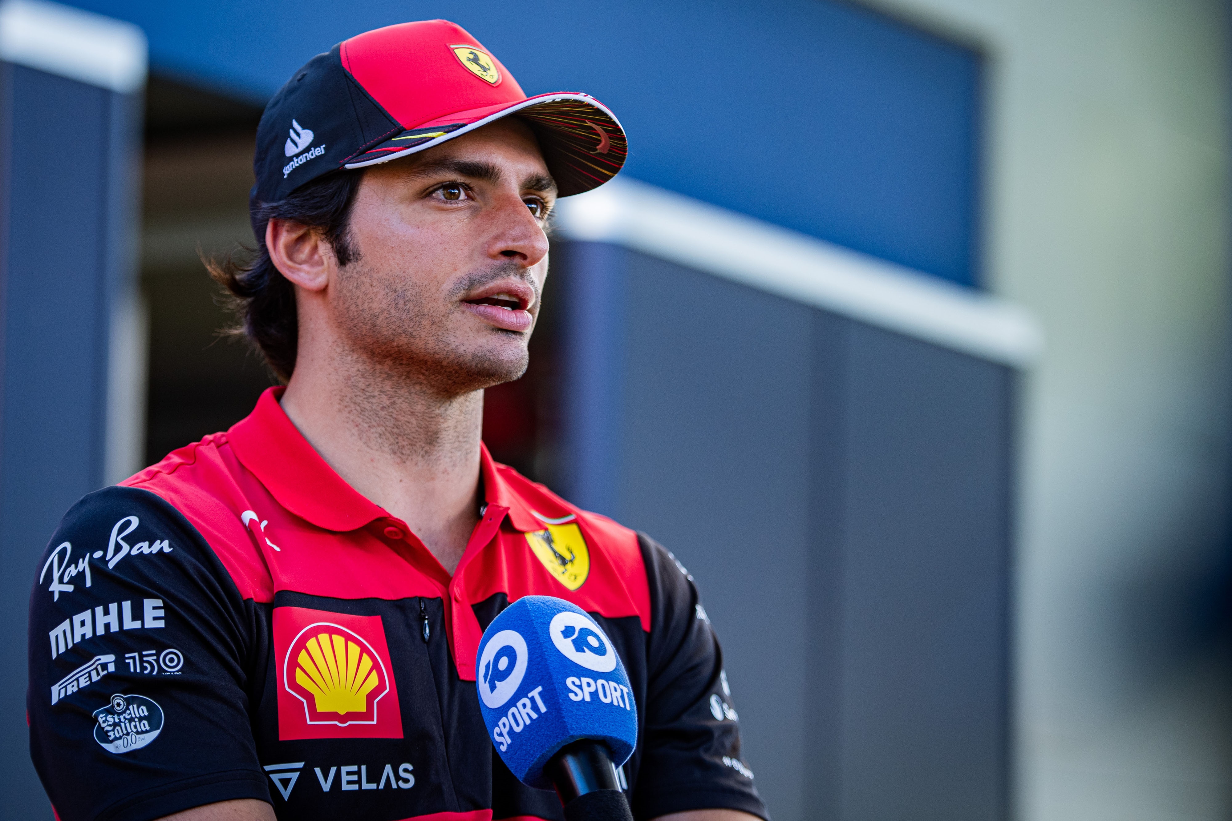 Carlos Sainz Jr. in Ferrari racing suit and cap HD Wallpaper