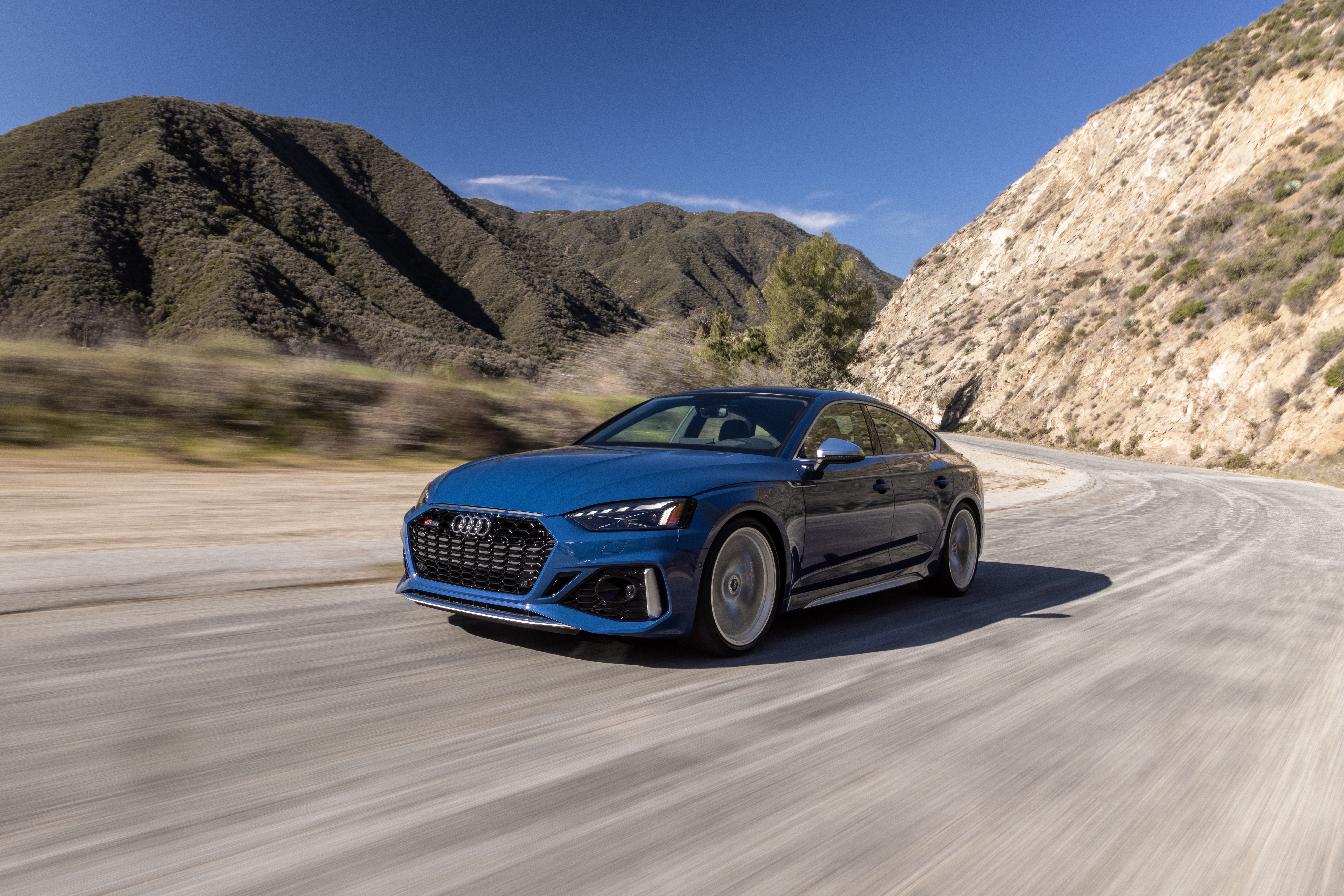 Blue Audi RS5 driving on a winding road HD Wallpaper