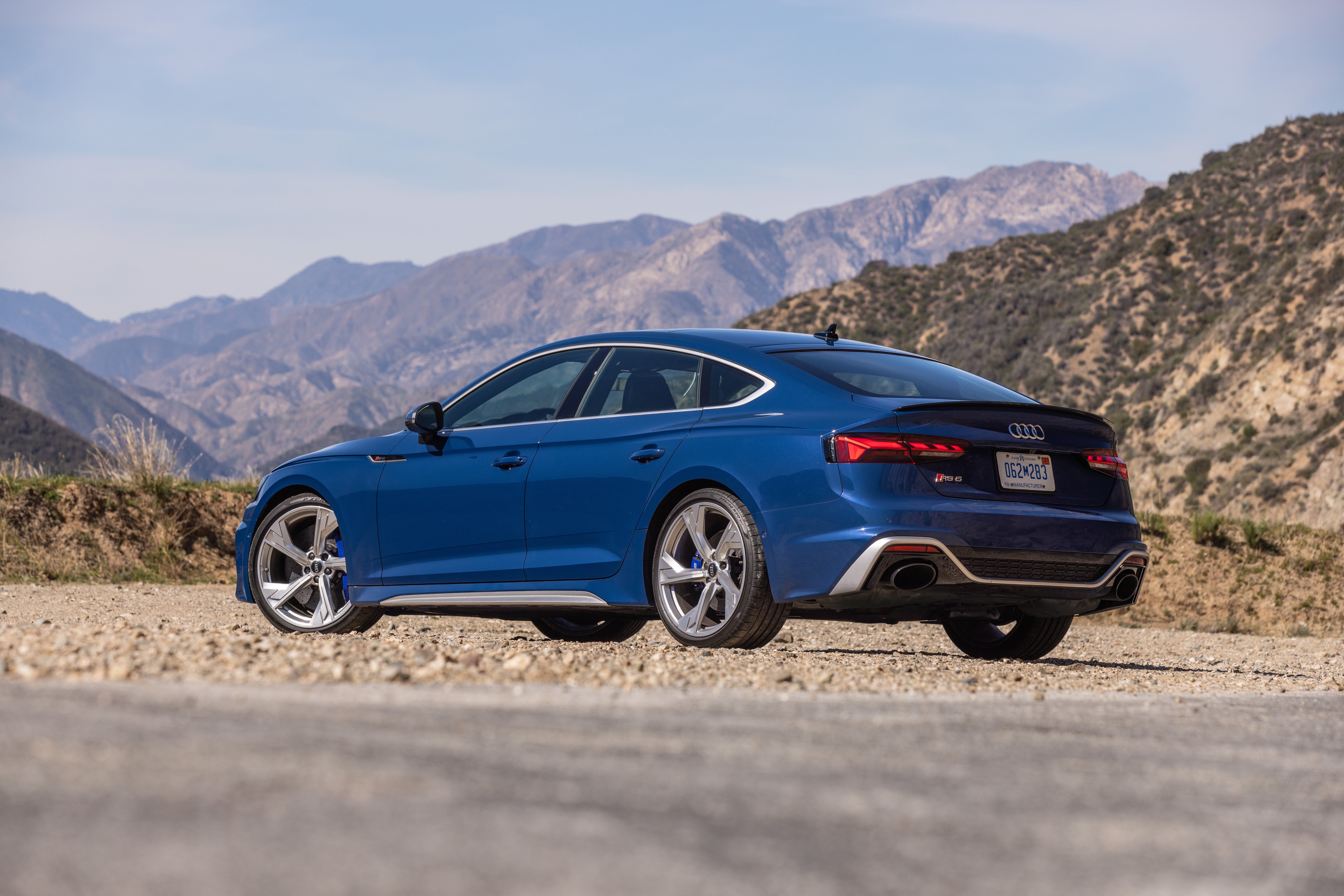 Blue Audi RS5 parked on a dirt road with mountains HD Wallpaper