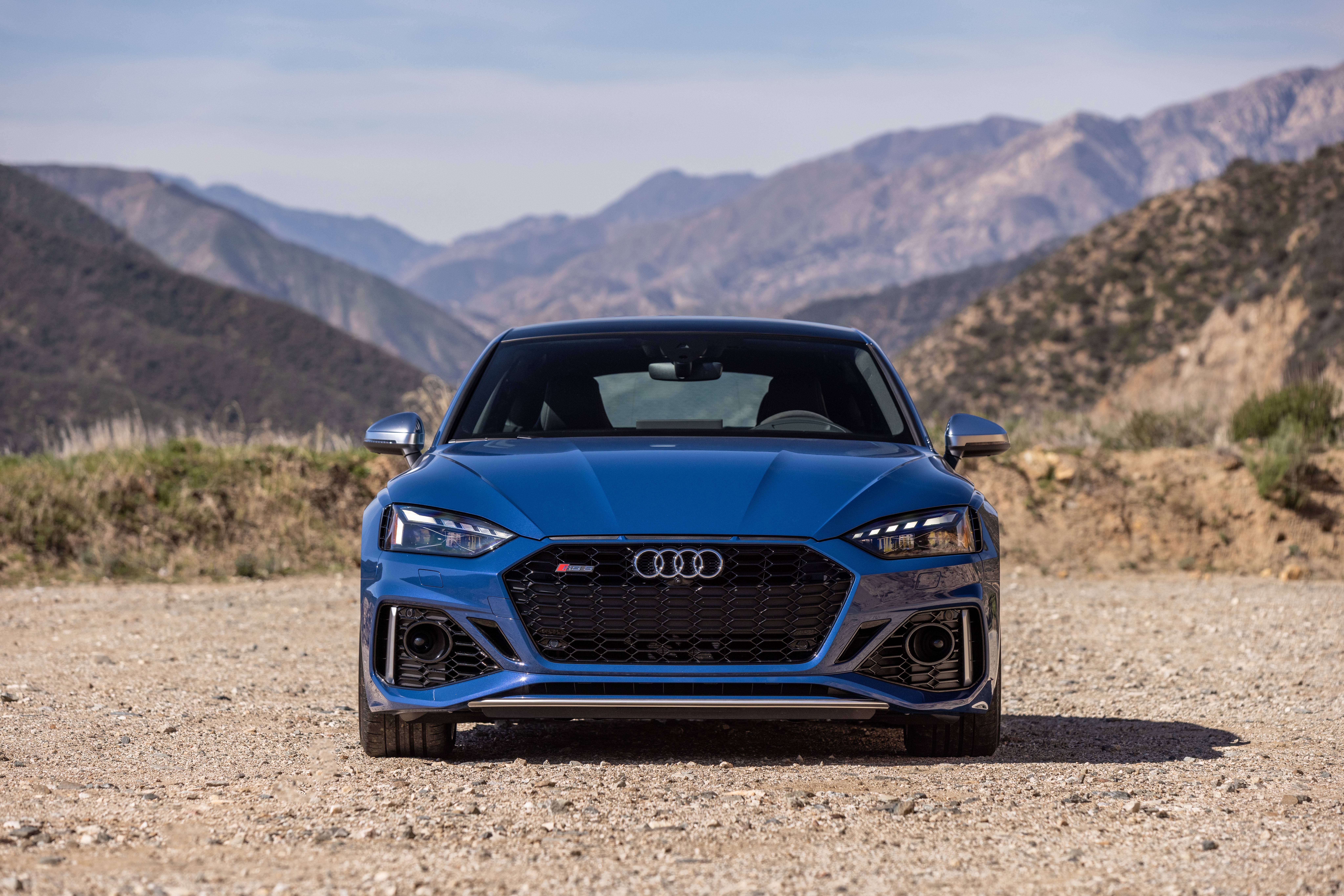 Blue Audi RS5 parked on a dirt road with mountains HD Wallpaper