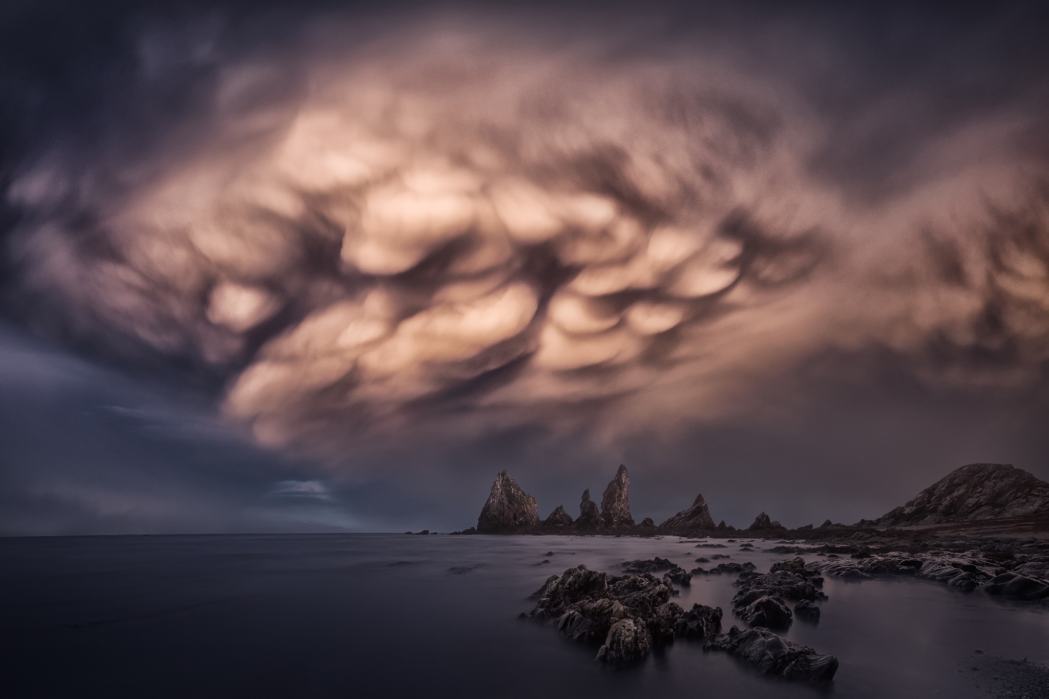 Mammatus clouds over rocky coastline HD Wallpaper