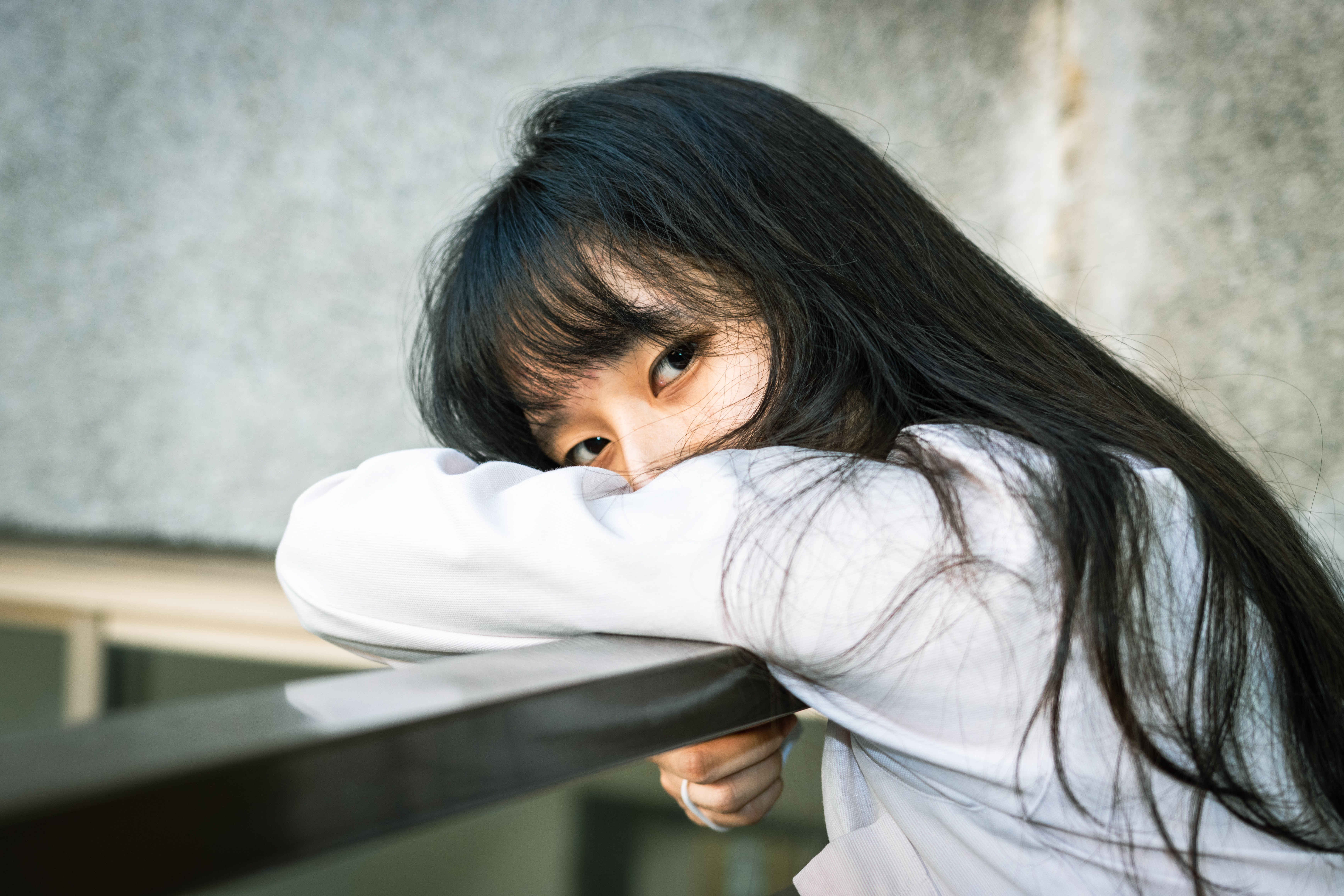 Asian girl resting her head on a railing HD Wallpaper