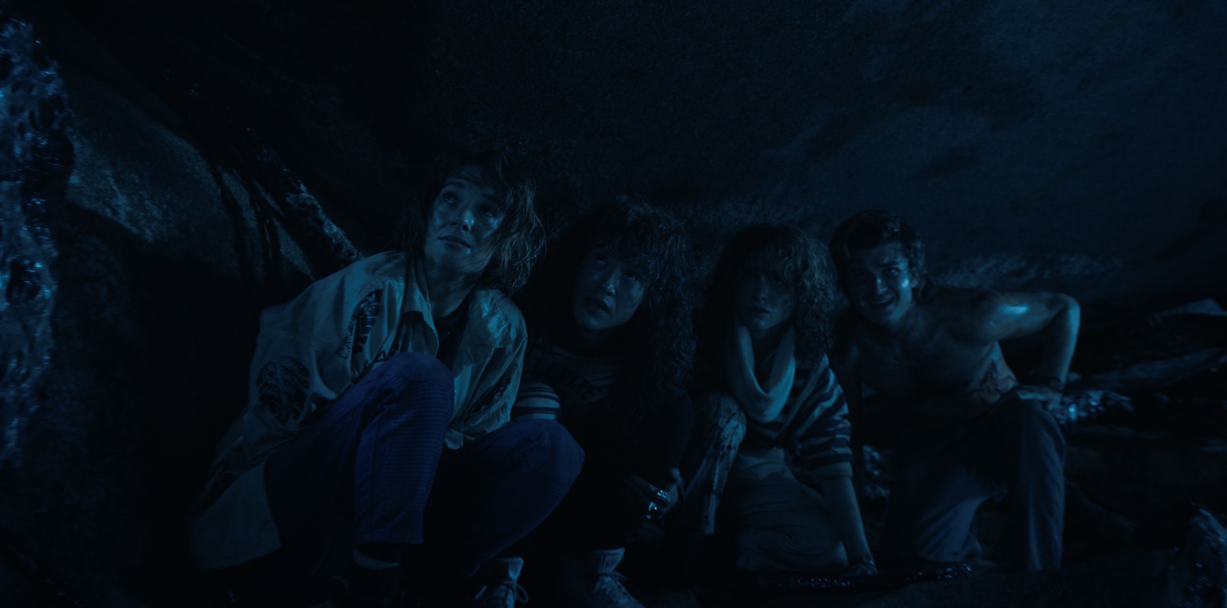 Four people hiding in a dark cave HD Wallpaper