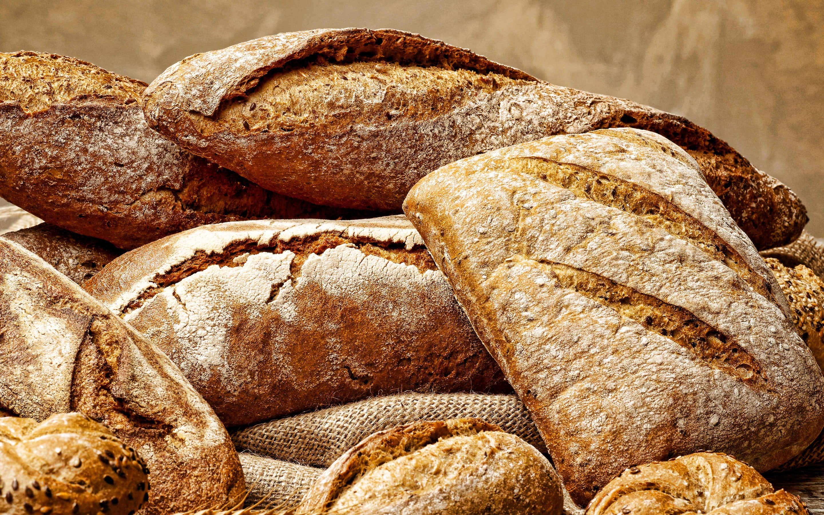 Pile of freshly baked artisan bread loaves HD Wallpaper