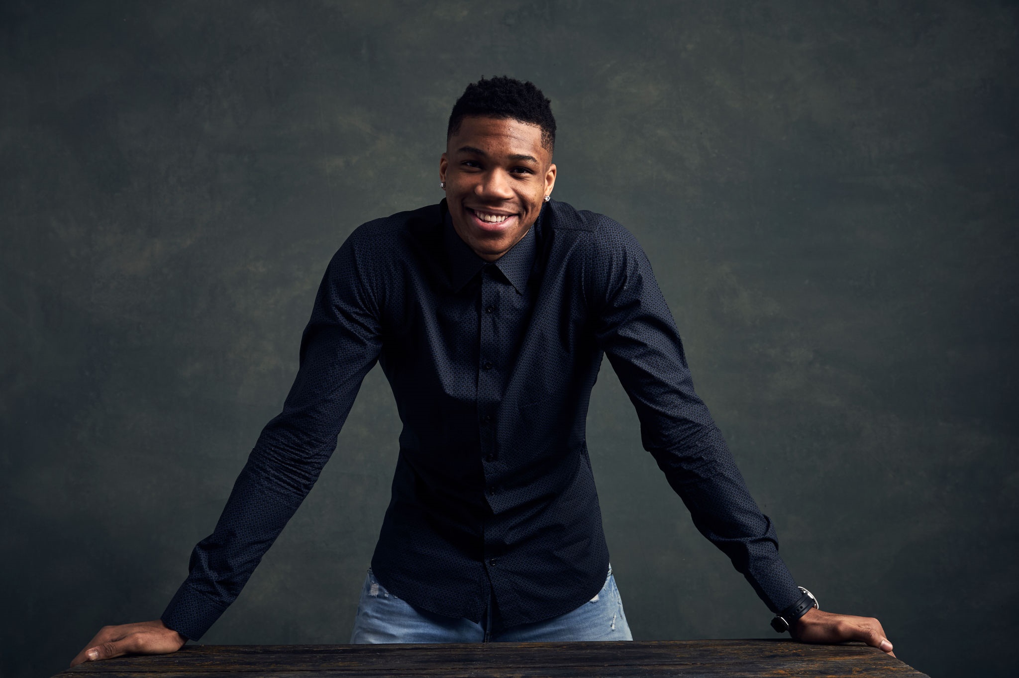 Giannis Antetokounmpo leaning on a wooden table HD Wallpaper