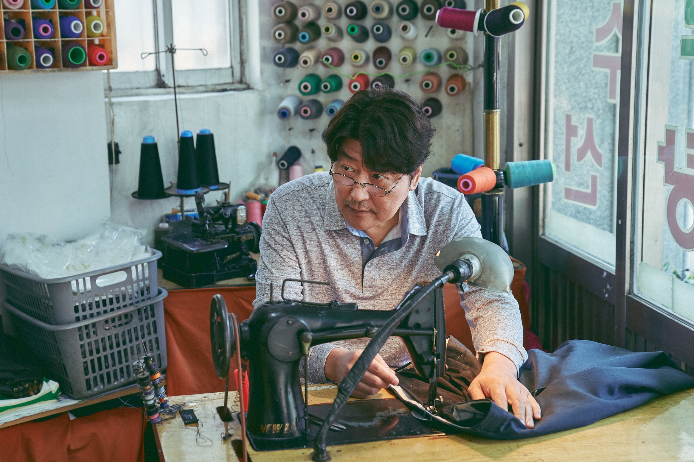 Man sewing at a sewing machine in a tailor shop HD Wallpaper
