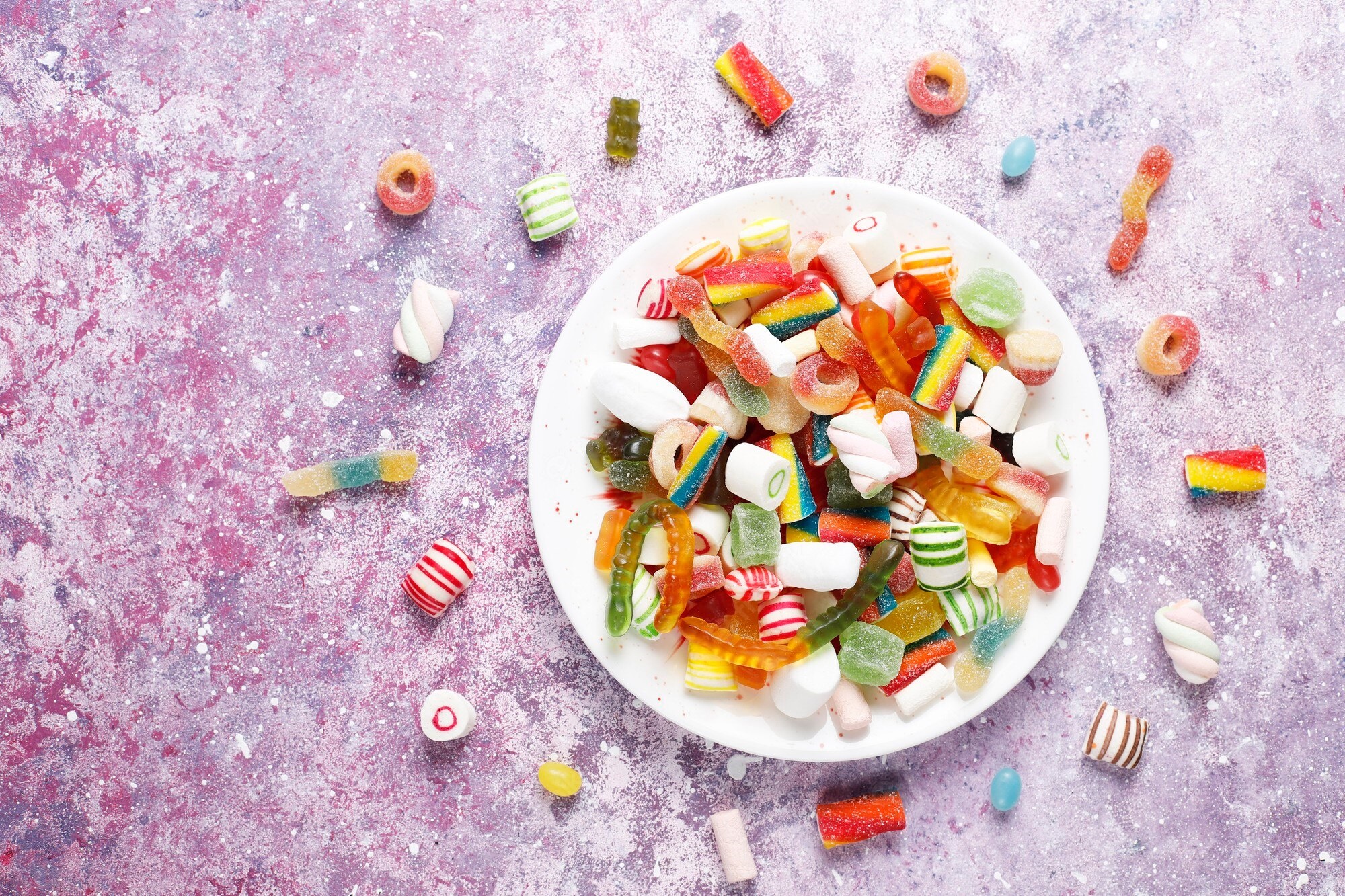 Assortment of colorful candies on a textured surface HD Wallpaper