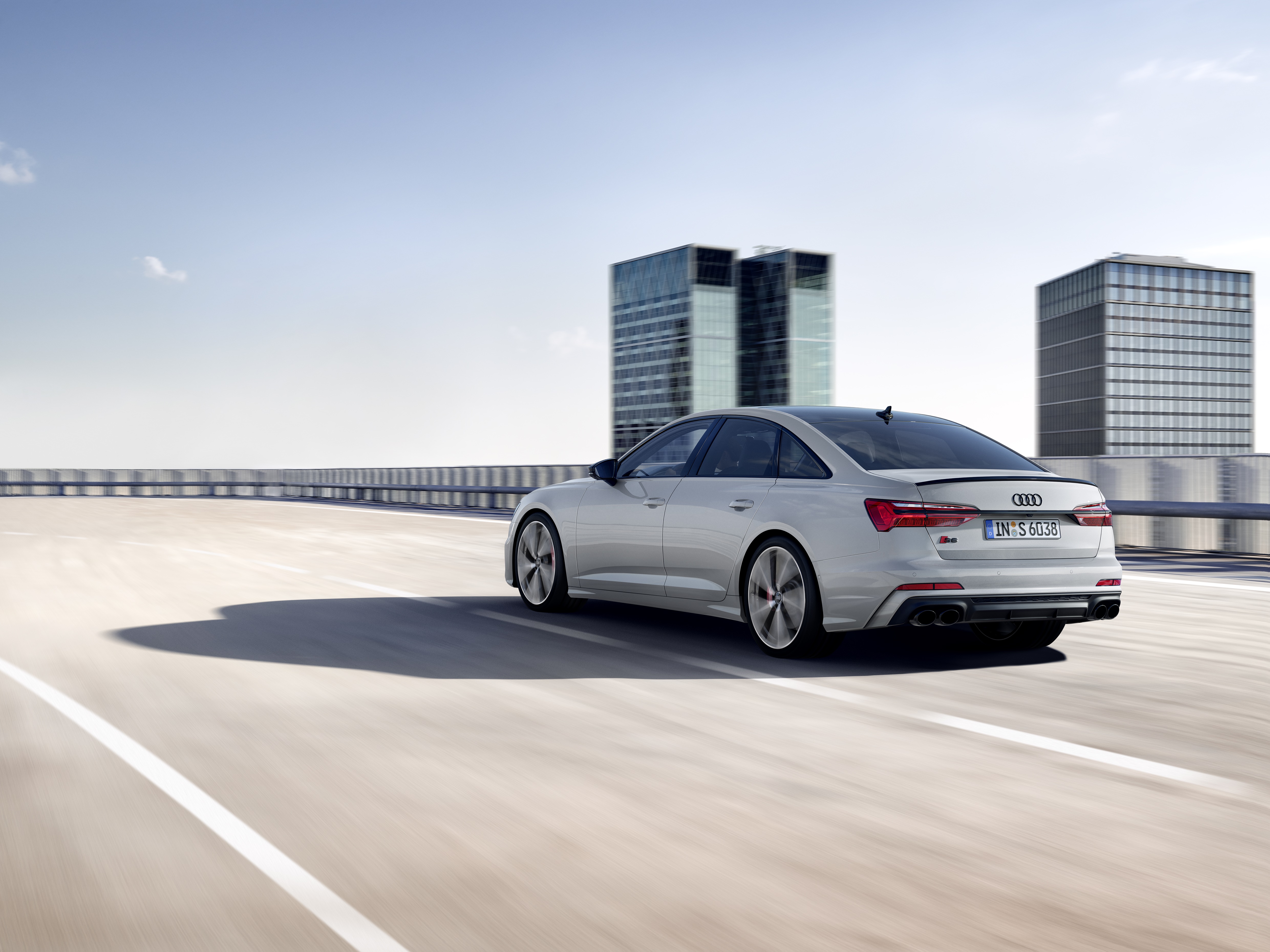 Audi S6 driving on a highway with city buildings HD Wallpaper