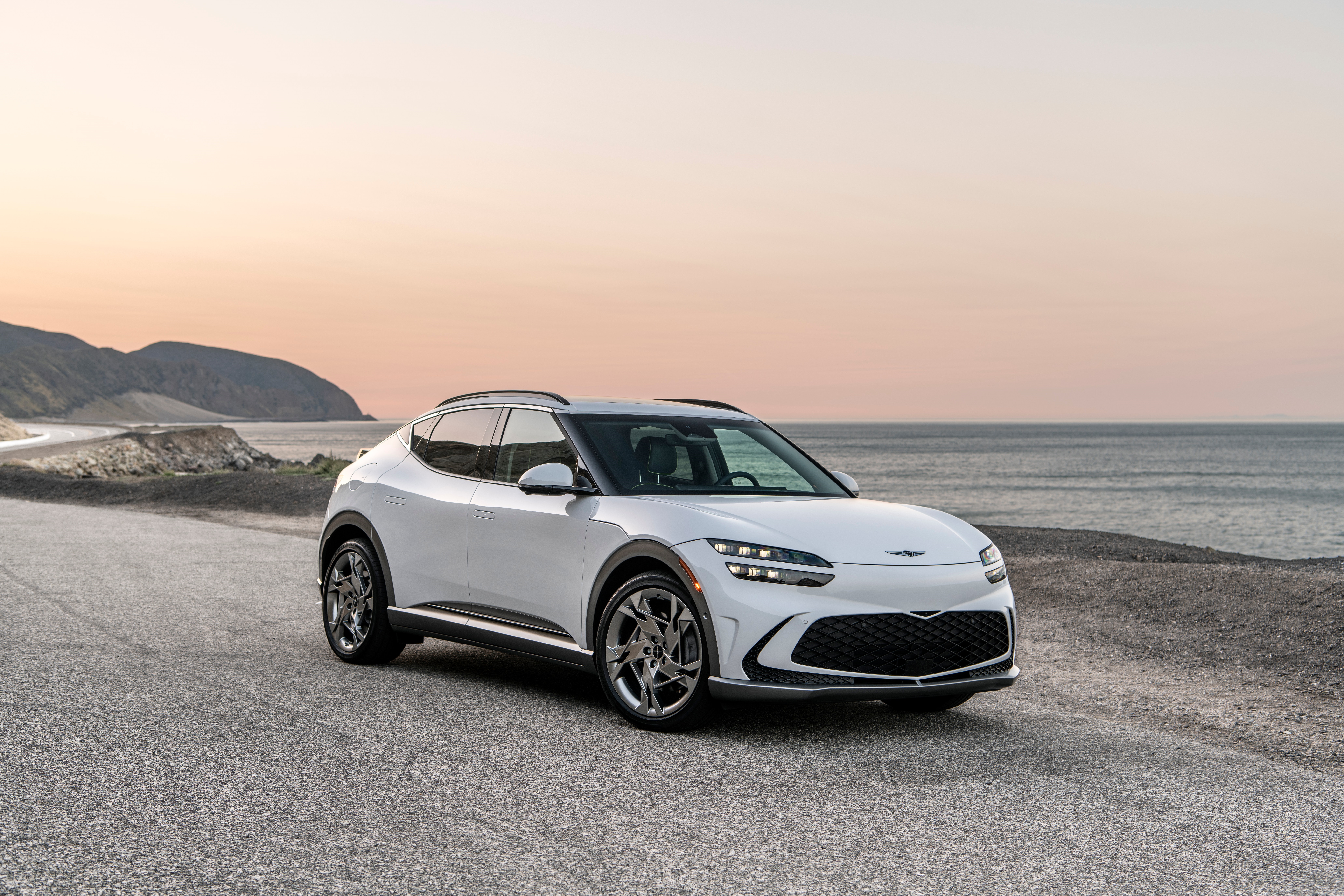 White Genesis GV60 parked on a coastal road HD Wallpaper
