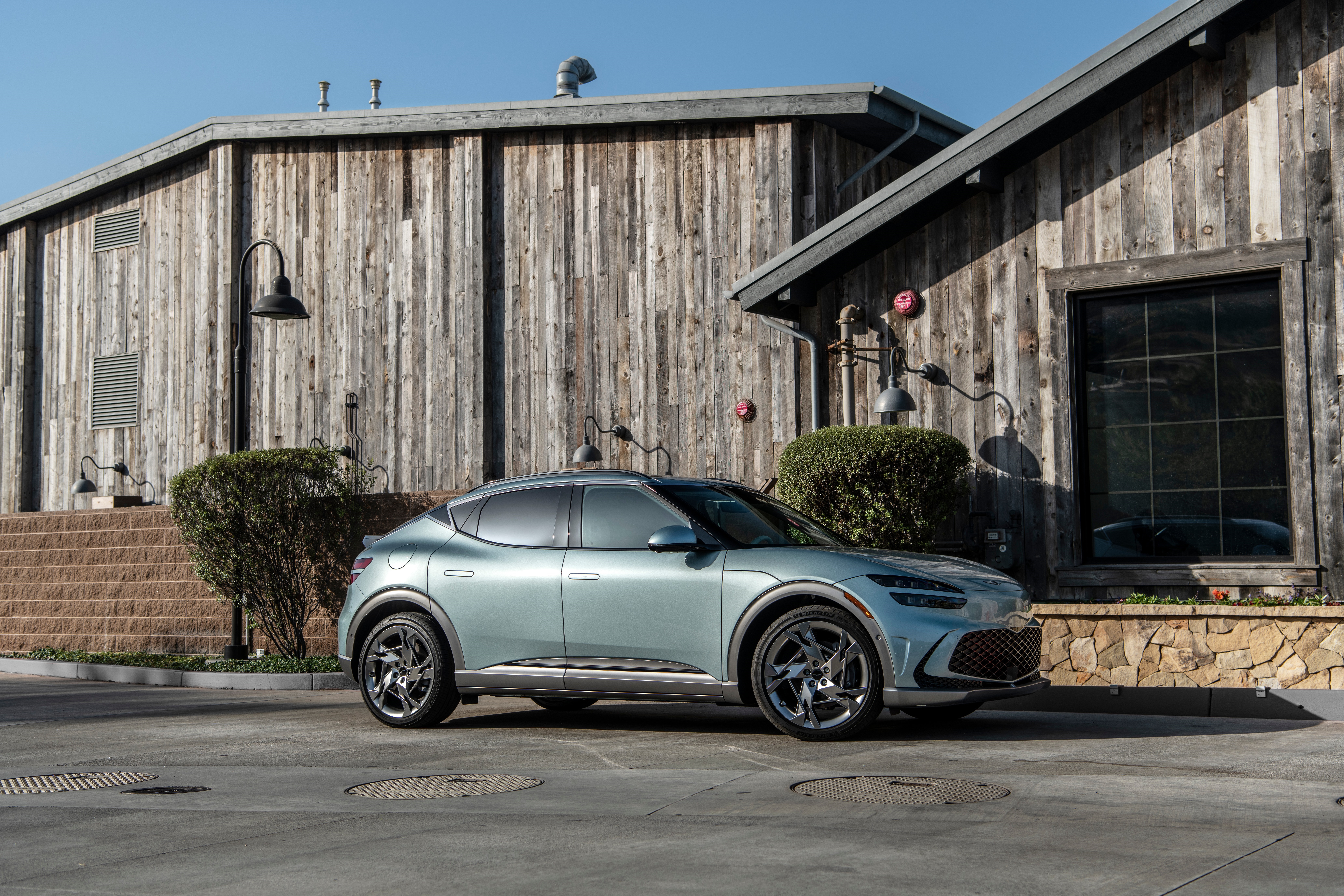 Genesis GV60 electric car parked near wooden building HD Wallpaper