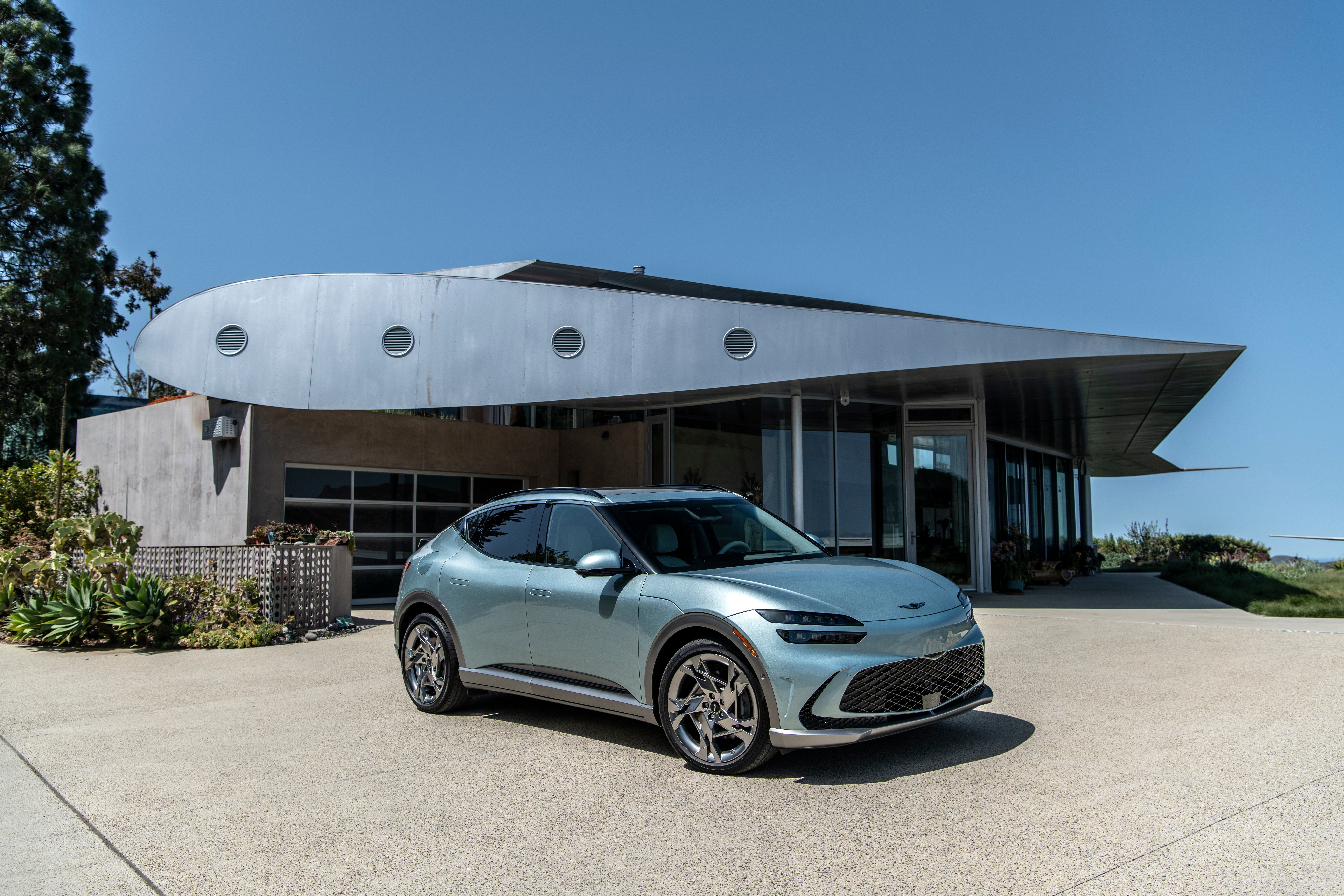 Genesis GV60 in front of a modern building HD Wallpaper