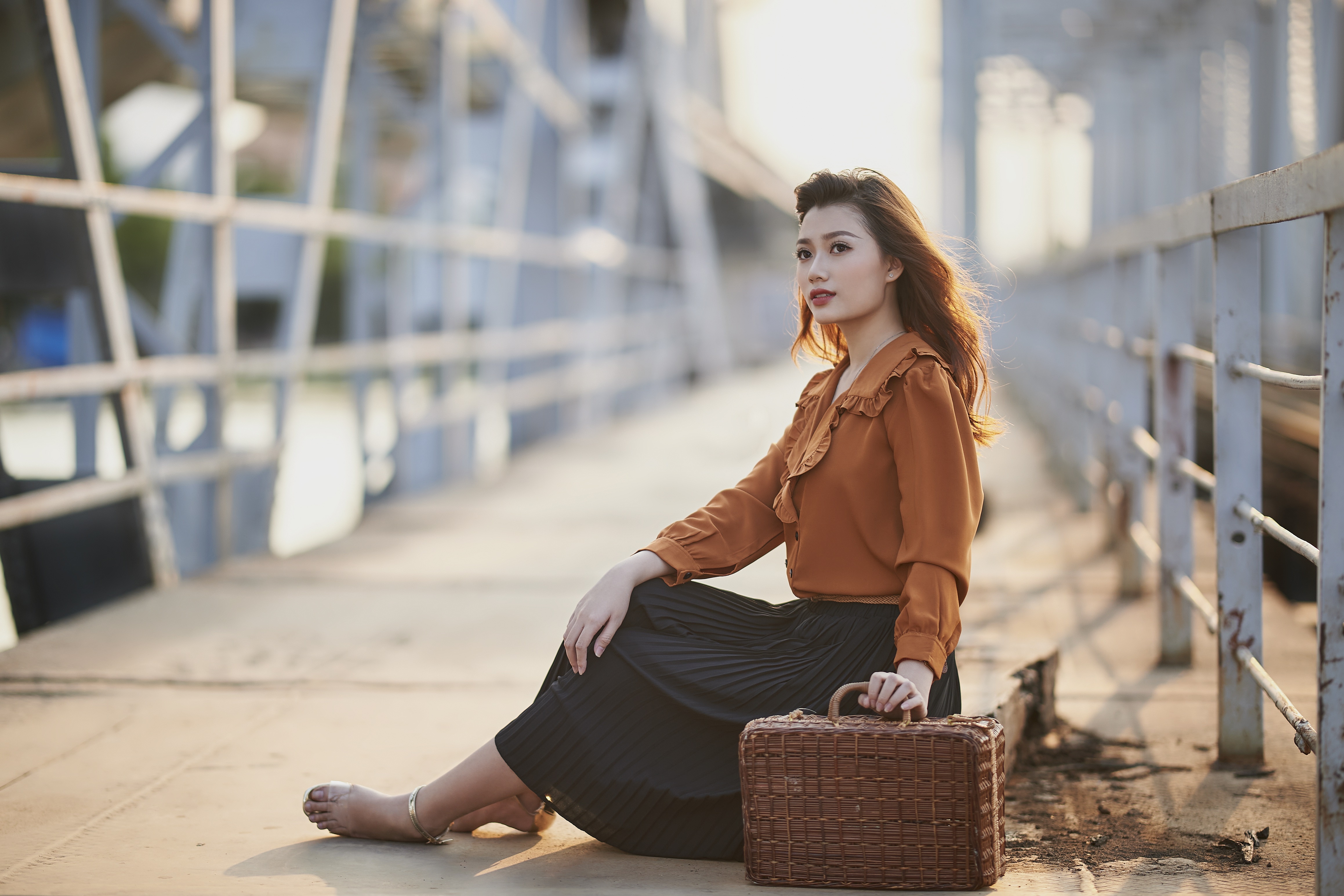 Asian woman sitting on a bridge with a suitcase HD Wallpaper