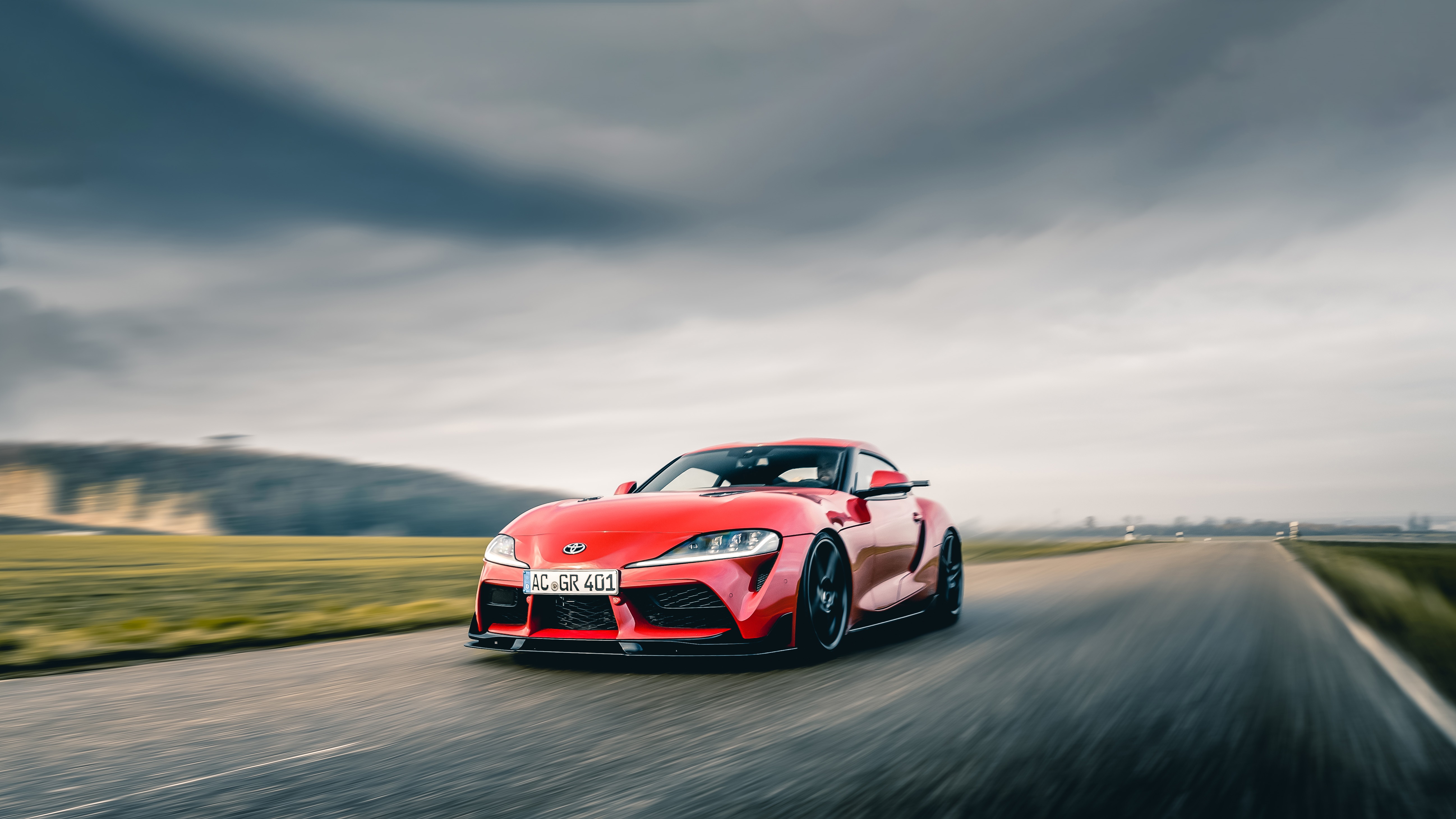 Red Toyota Supra GR 401 driving on a road HD Wallpaper