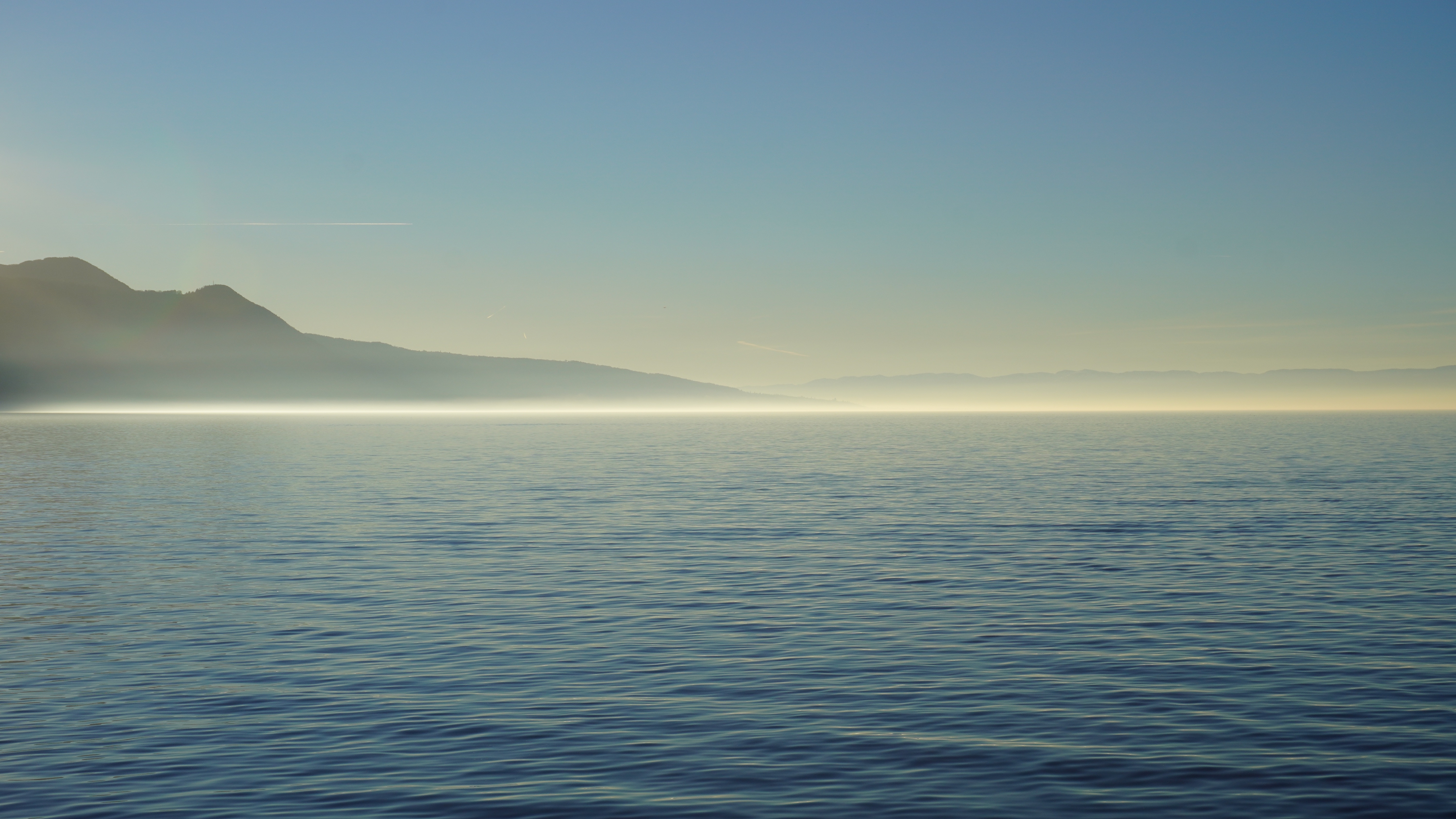 Lake and mountains shrouded in fog at sunrise HD Wallpaper