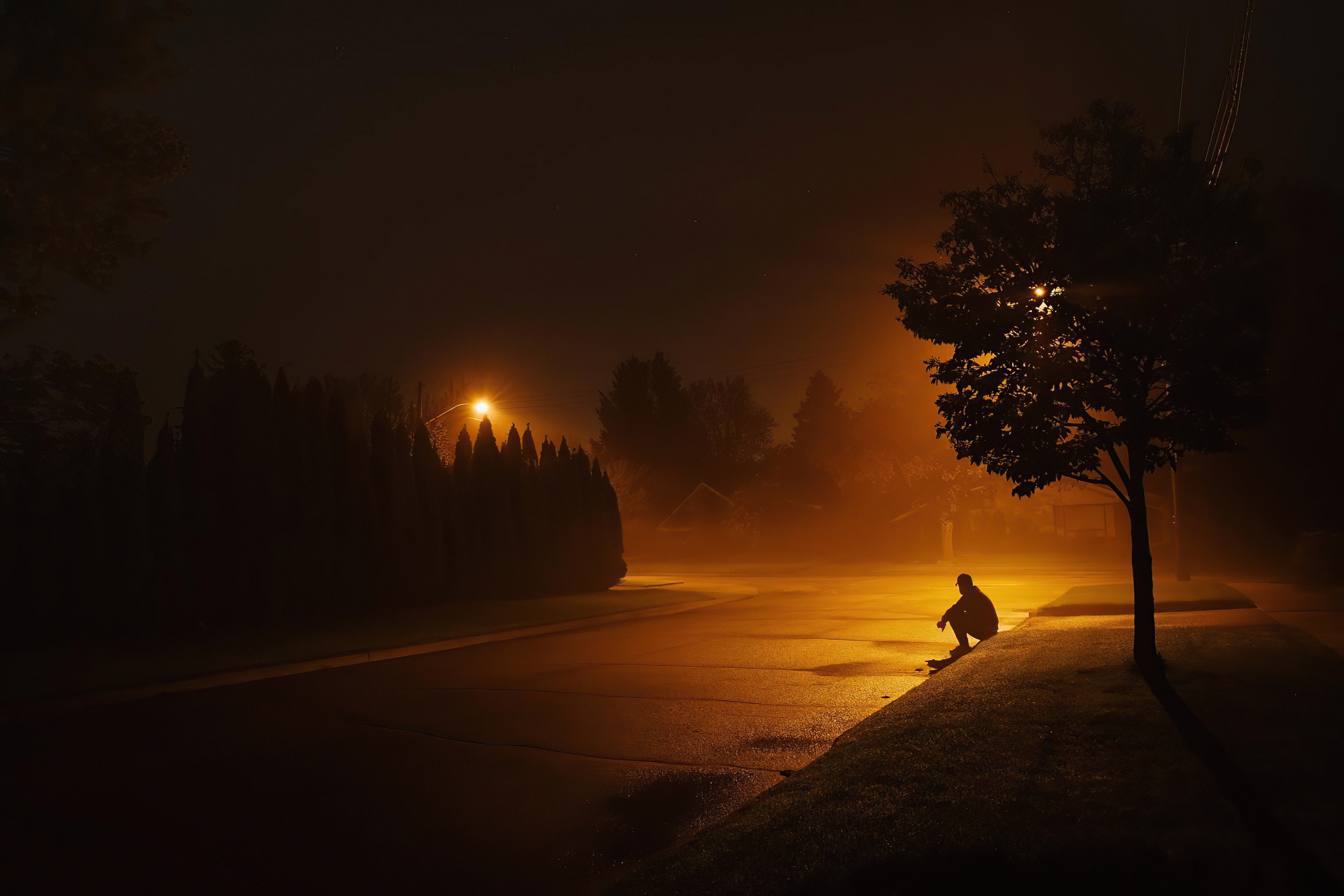 Man sitting by street light at night HD Wallpaper