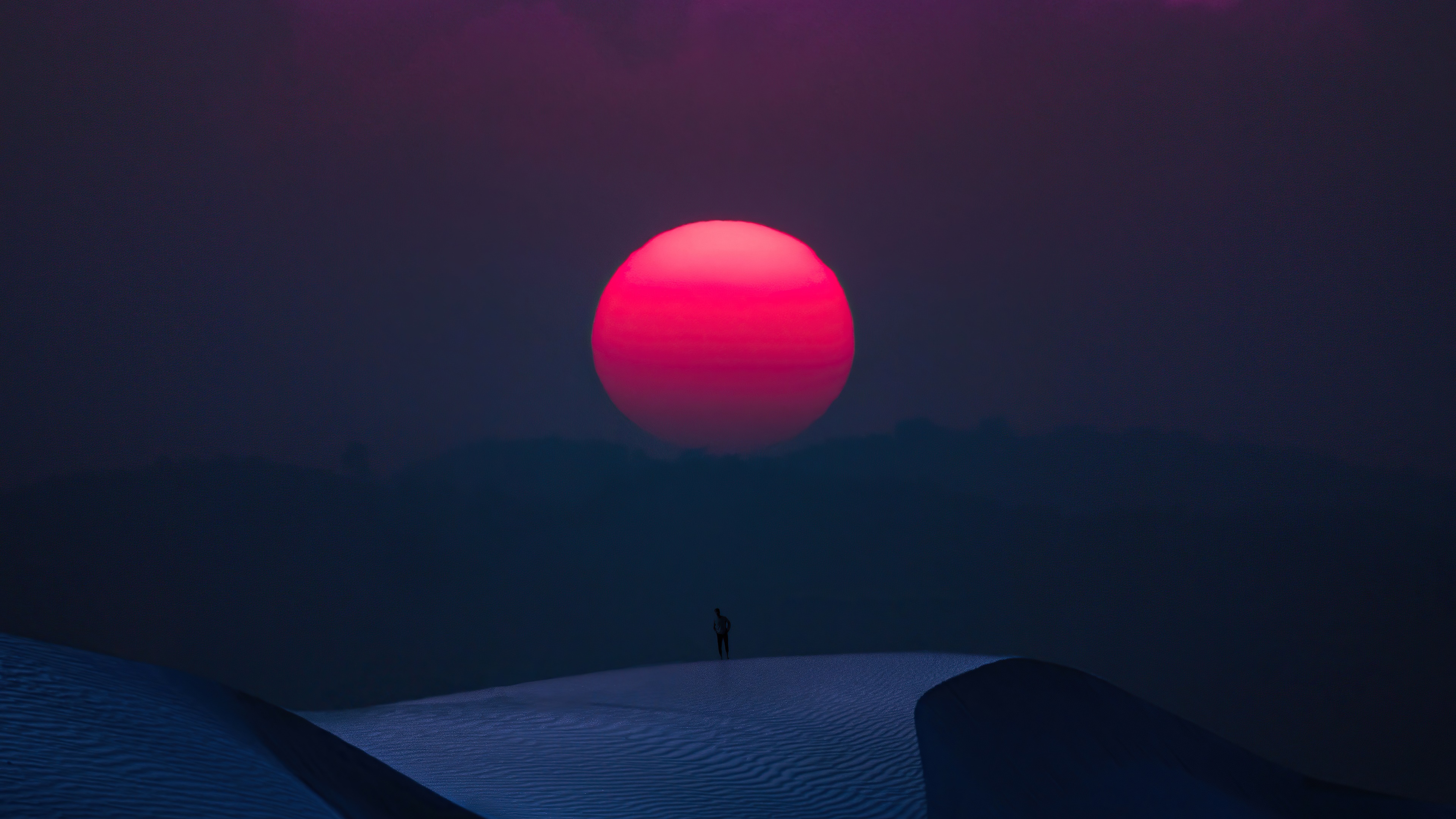 Man standing on sand dunes with large red sun HD Wallpaper
