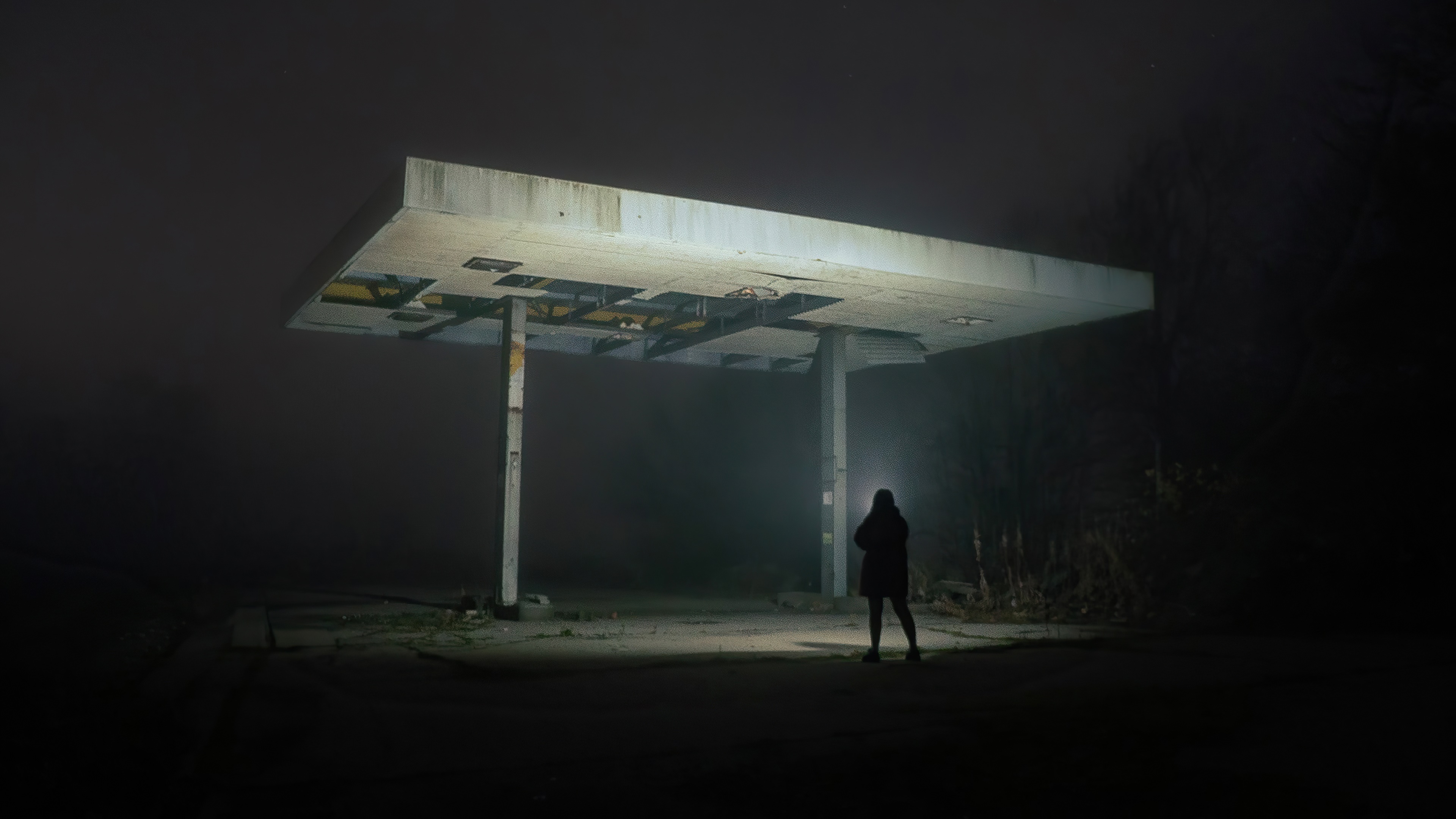 Person with flashlight at abandoned gas station HD Wallpaper