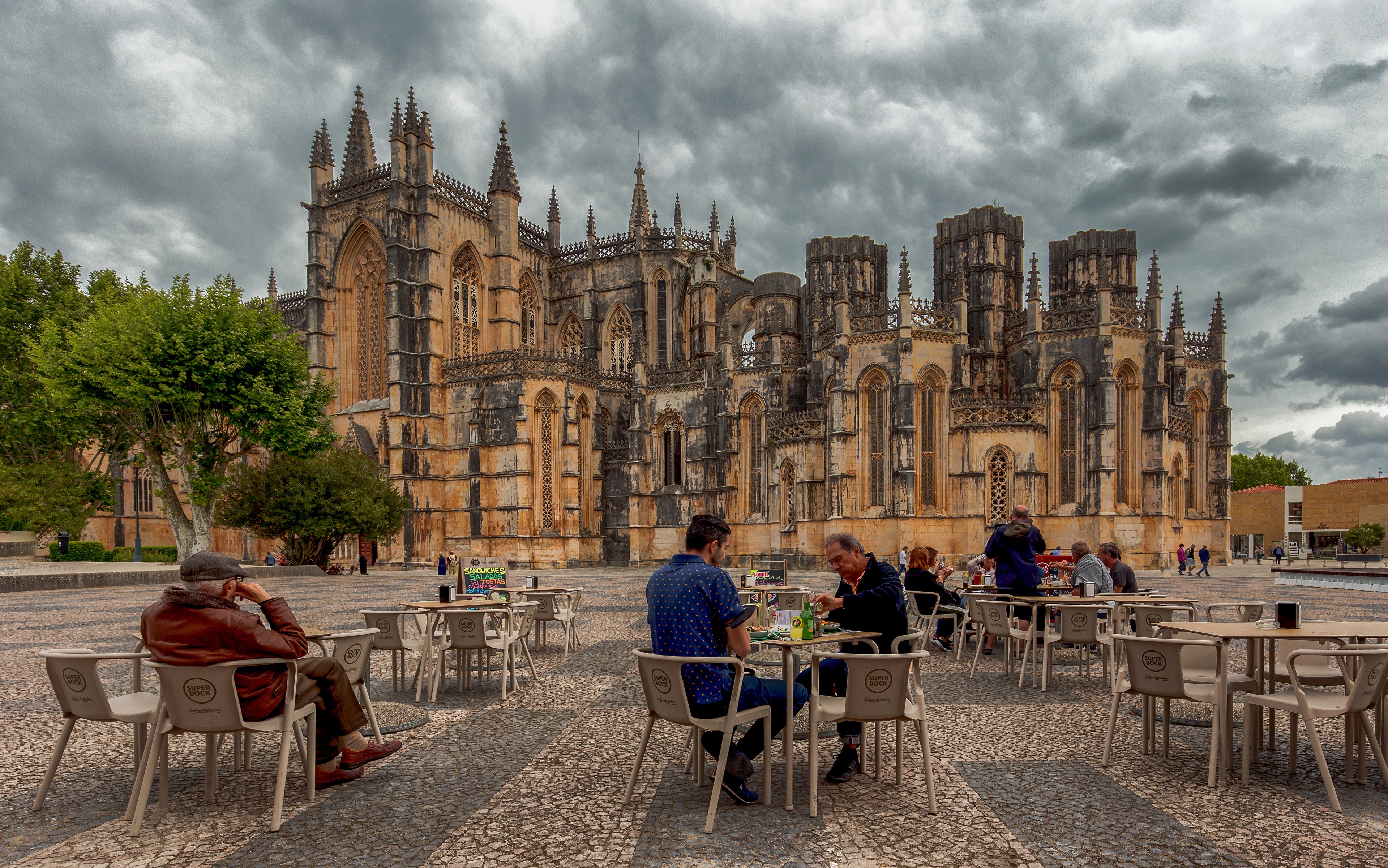 People at Cafe in front of Batalha Monastery, Portugal HD Wallpaper
