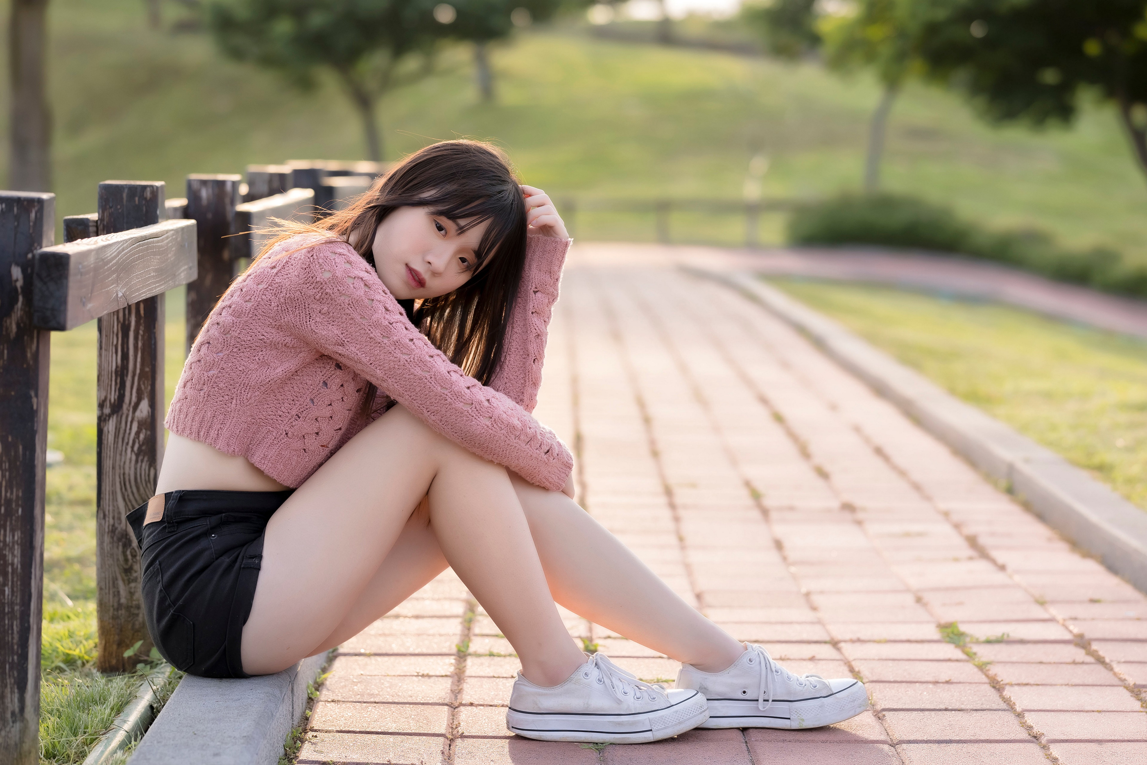 Asian girl sitting on a curb in a park HD Wallpaper