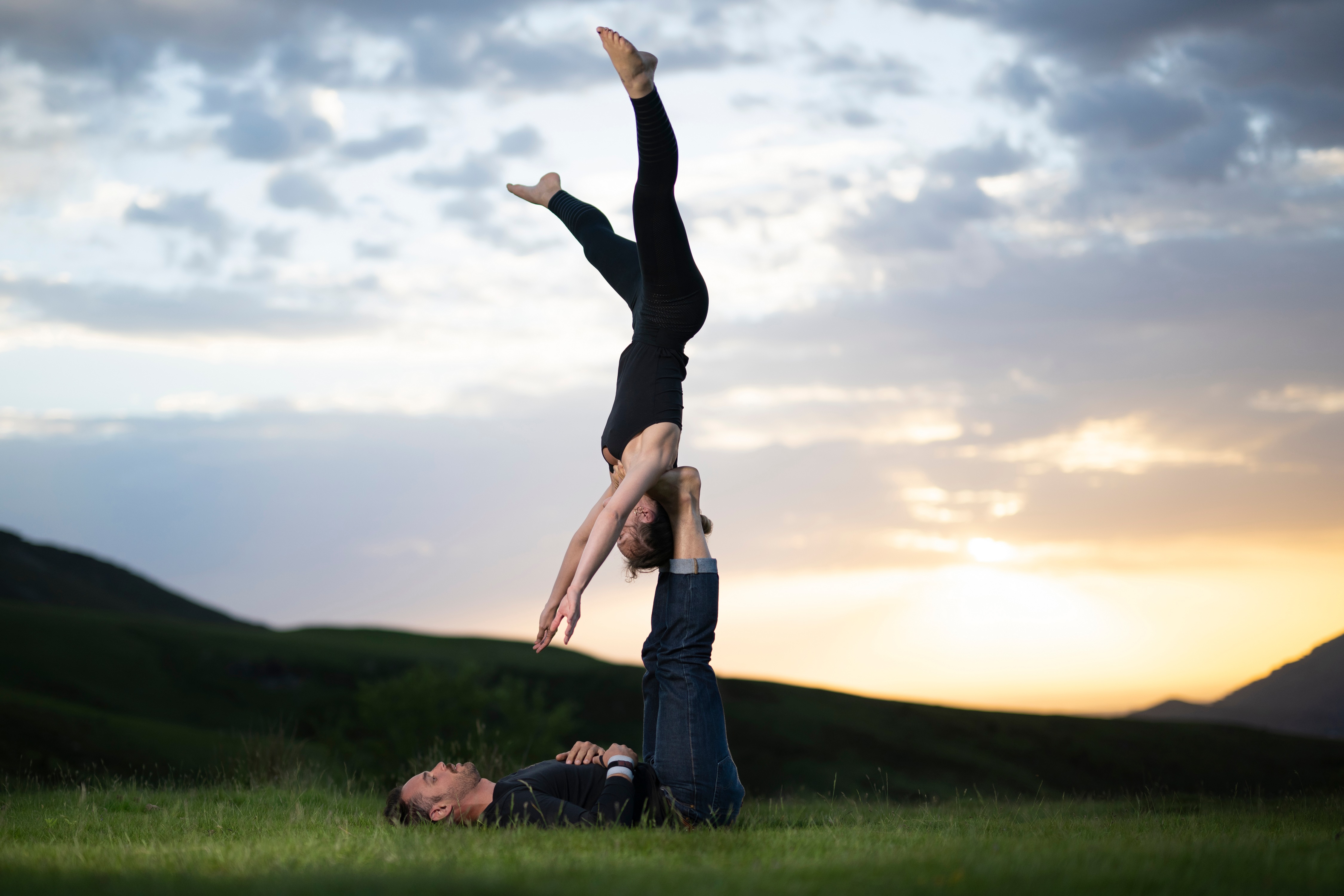 Acrobatics couple performing on grass at sunset HD Wallpaper