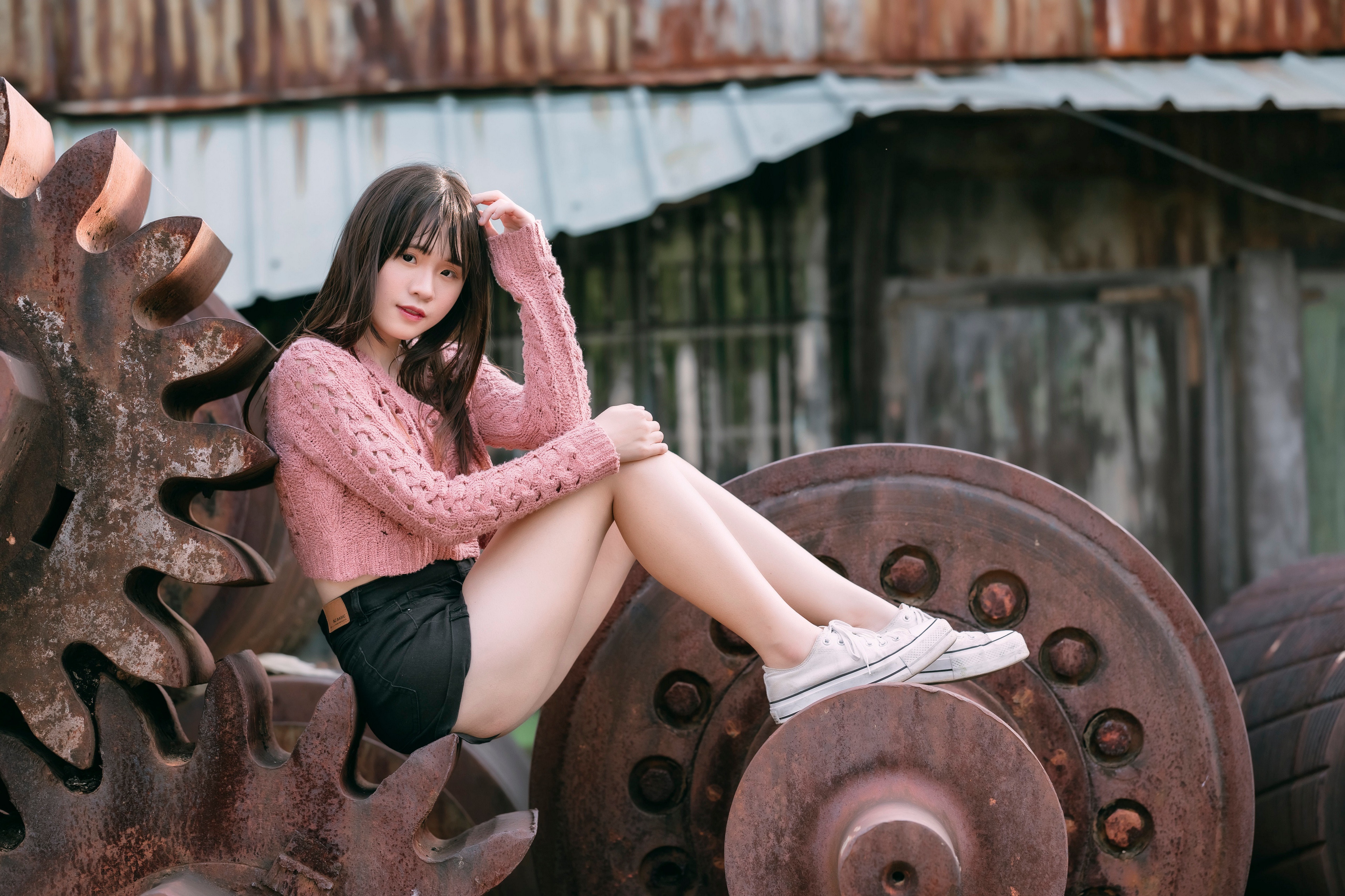 Asian girl in pink sweater and shorts sitting on gears HD Wallpaper