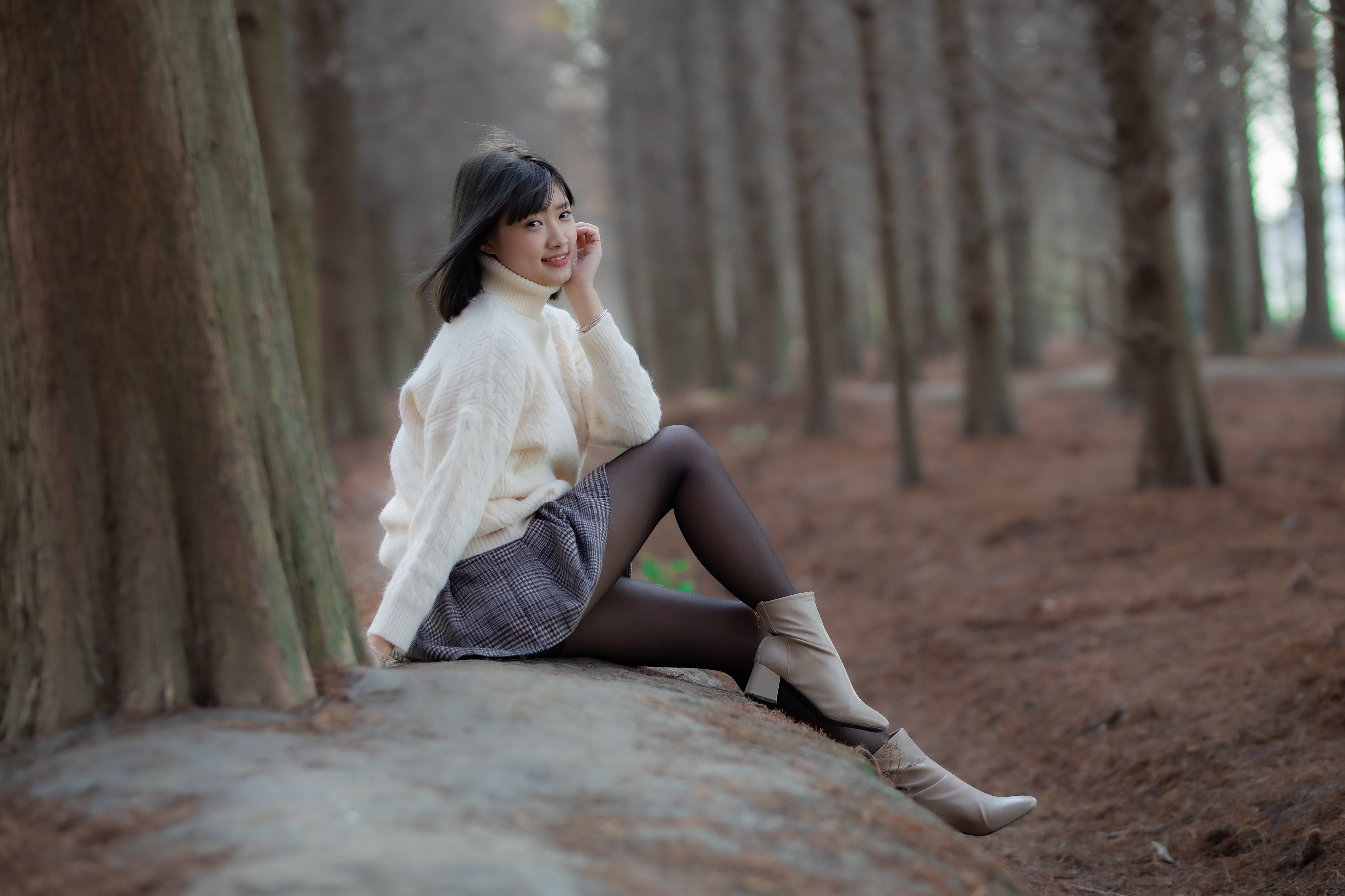 Asian girl in sweater and skirt sitting in forest HD Wallpaper