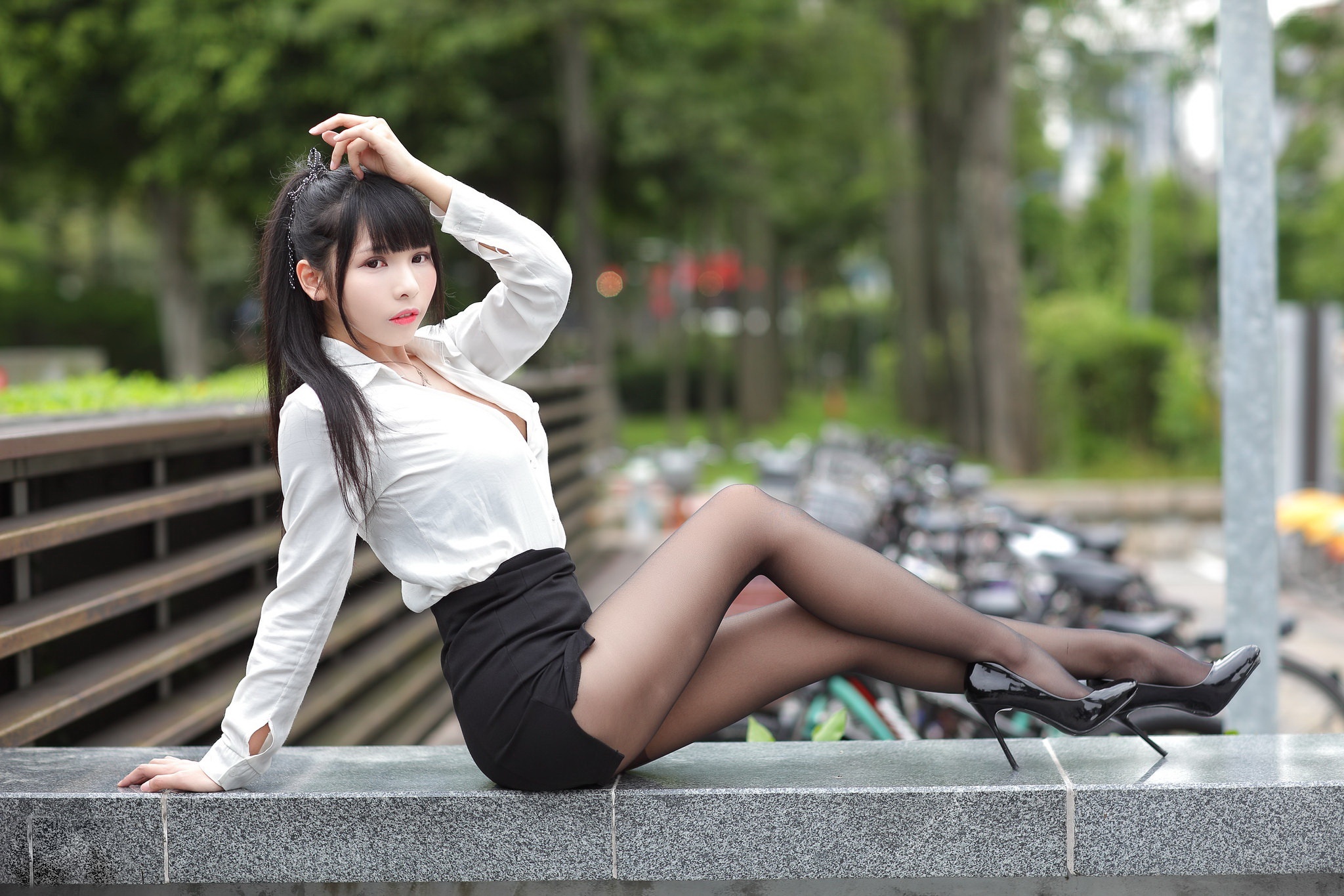 Asian woman in blouse and skirt sitting outdoors HD Wallpaper