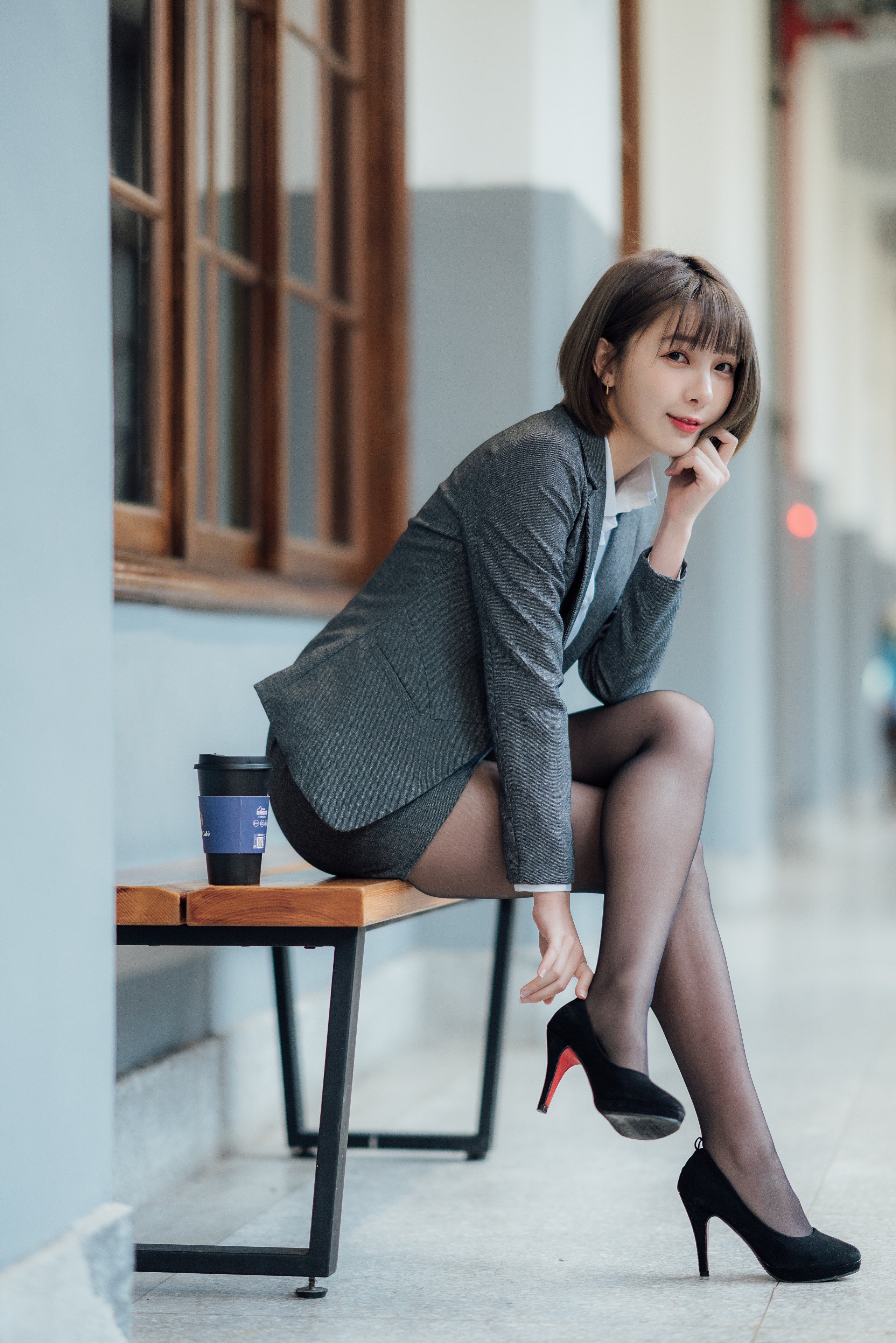 Asian woman in suit sitting on bench with coffee HD Phone Wallpaper