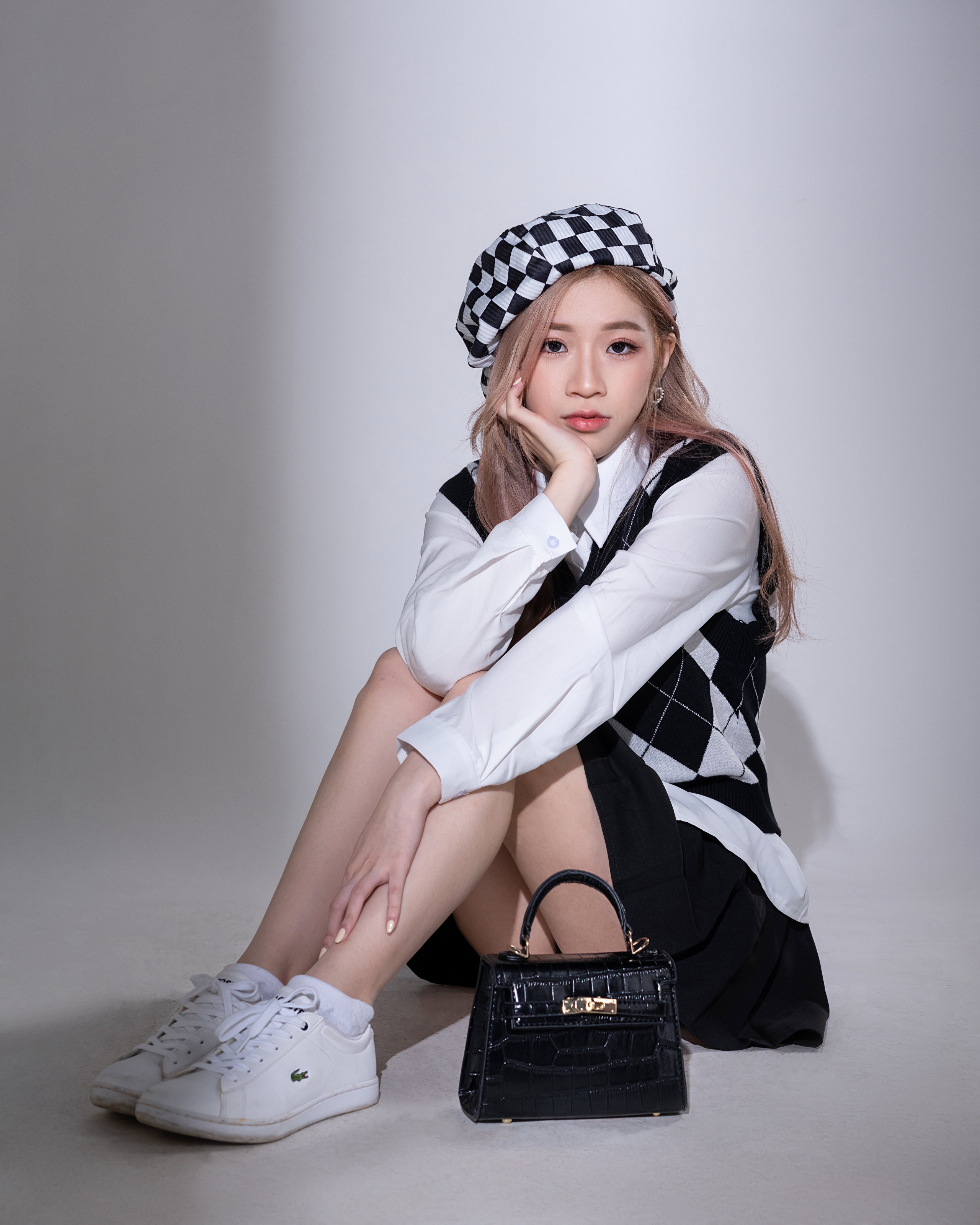 Asian woman wearing beret and vest, sitting with handbag HD Phone Wallpaper