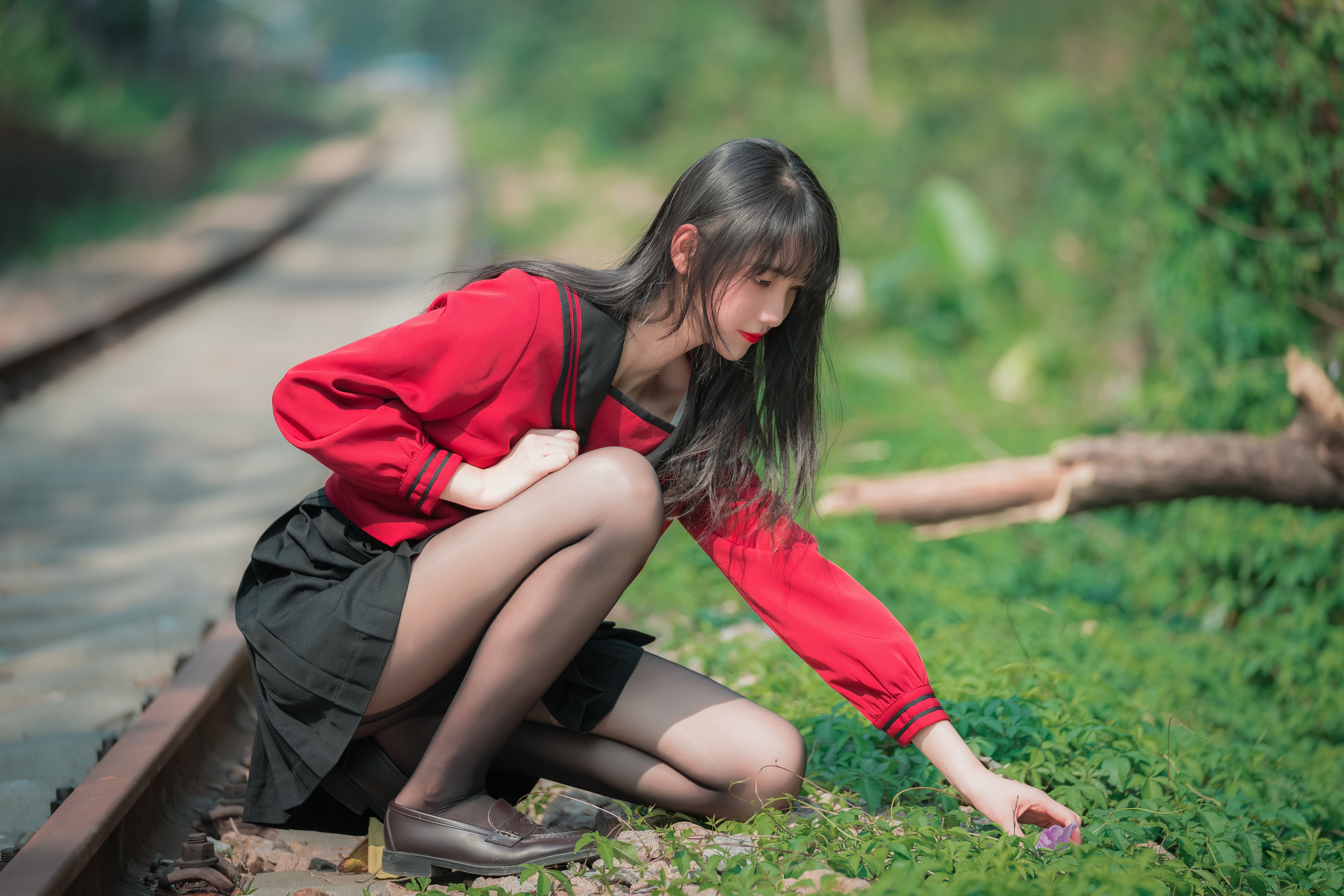 Brunette girl in red jacket and black skirt on train tracks HD Wallpaper