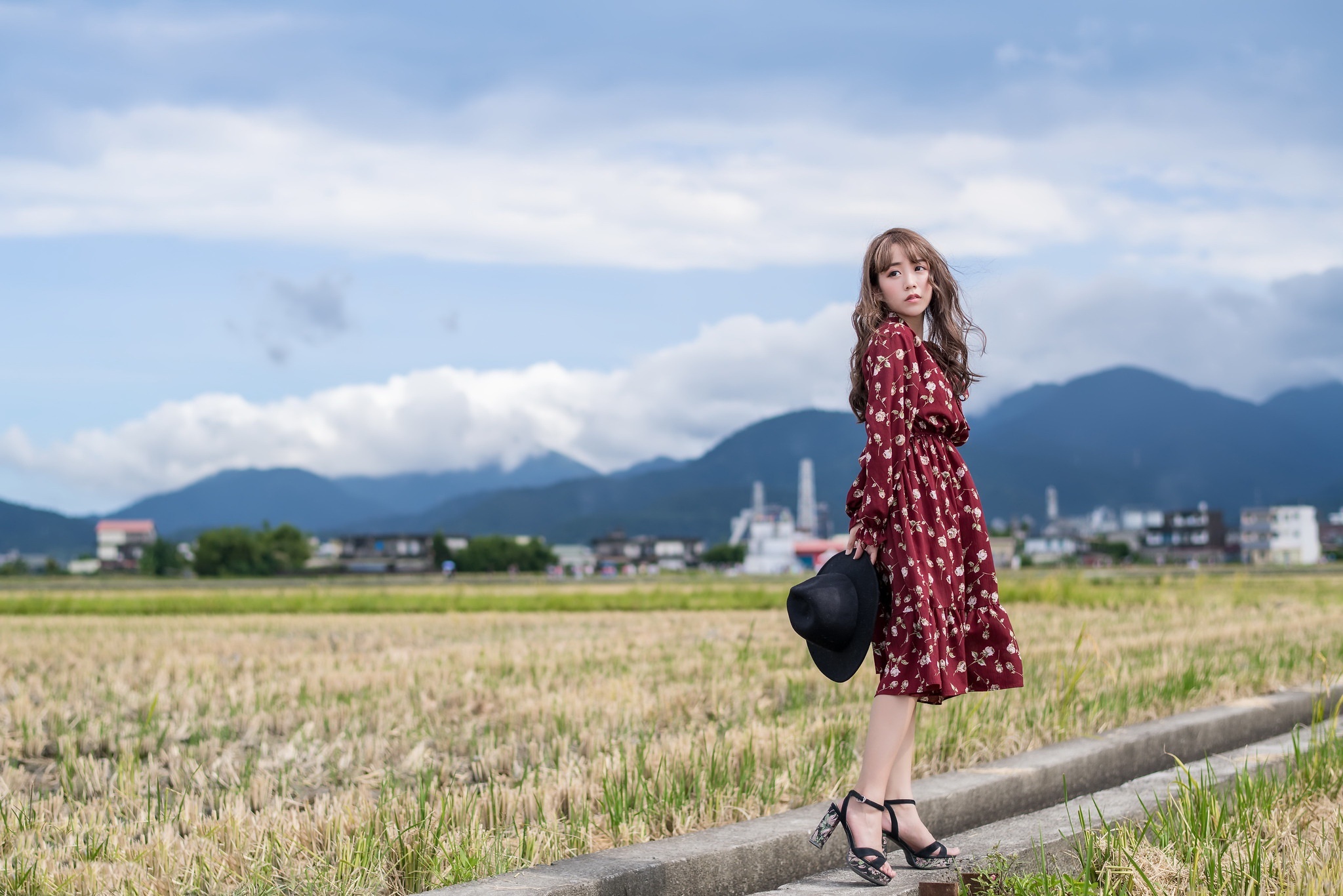 Woman in floral dress holding a hat in a field HD Wallpaper