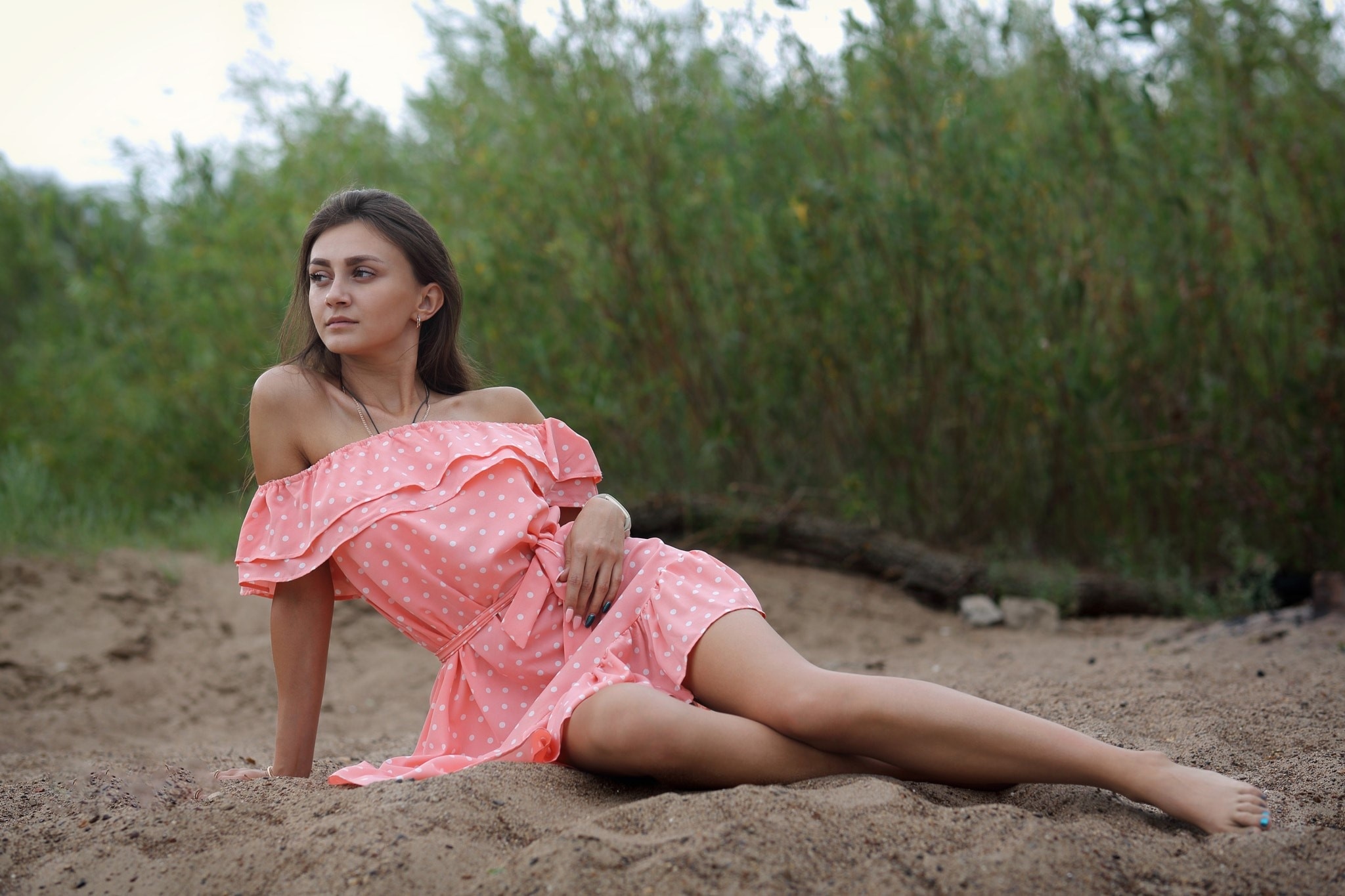 Woman in pink polka dot dress lying on sand HD Wallpaper