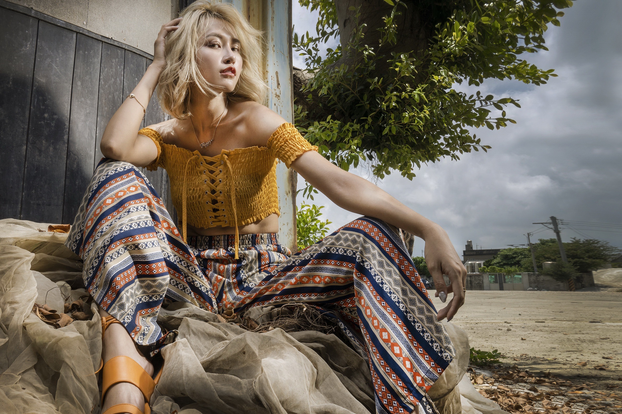Blonde Asian woman sitting in patterned pants HD Wallpaper