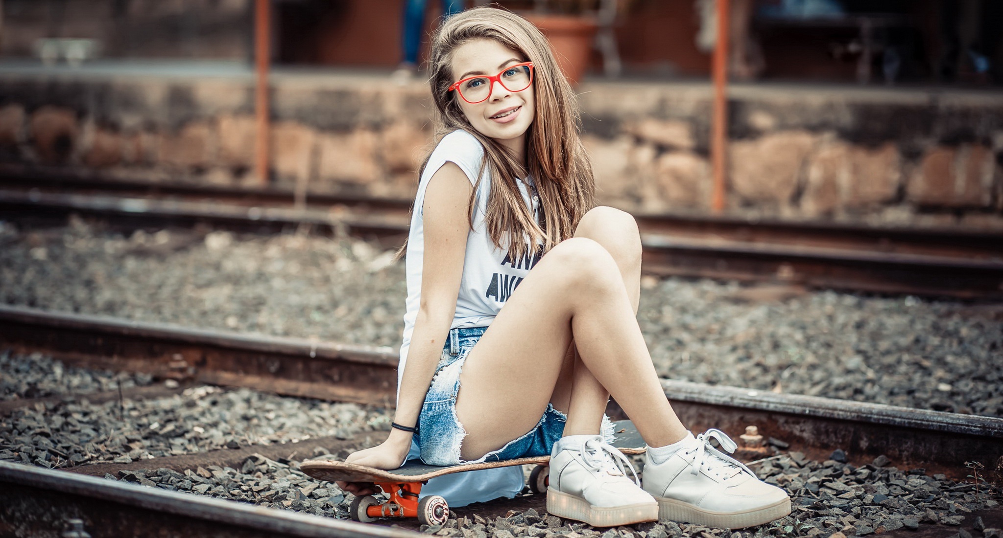 Girl with skateboard sitting on train tracks HD Wallpaper