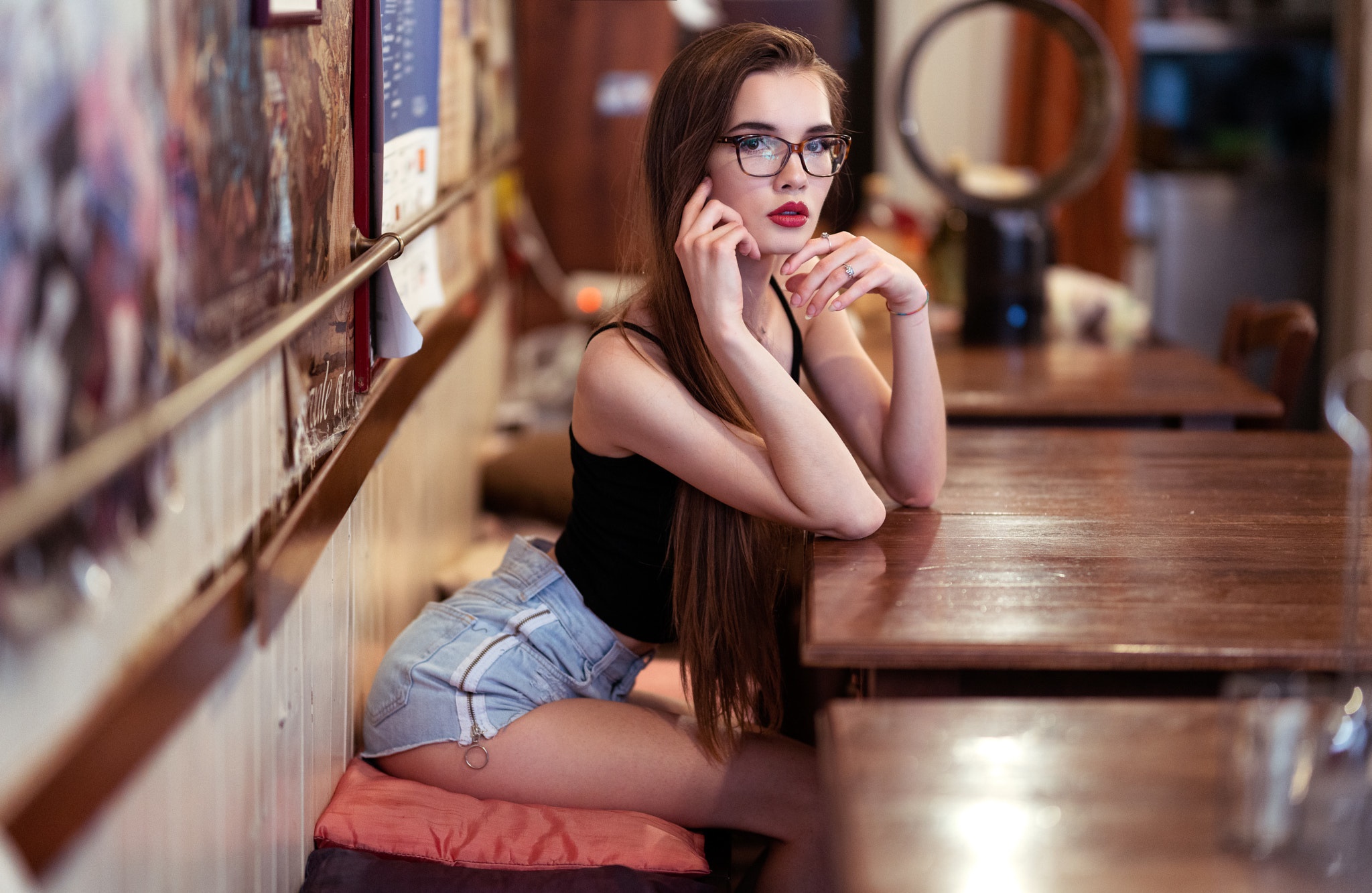 Woman with glasses sitting at a table HD Wallpaper