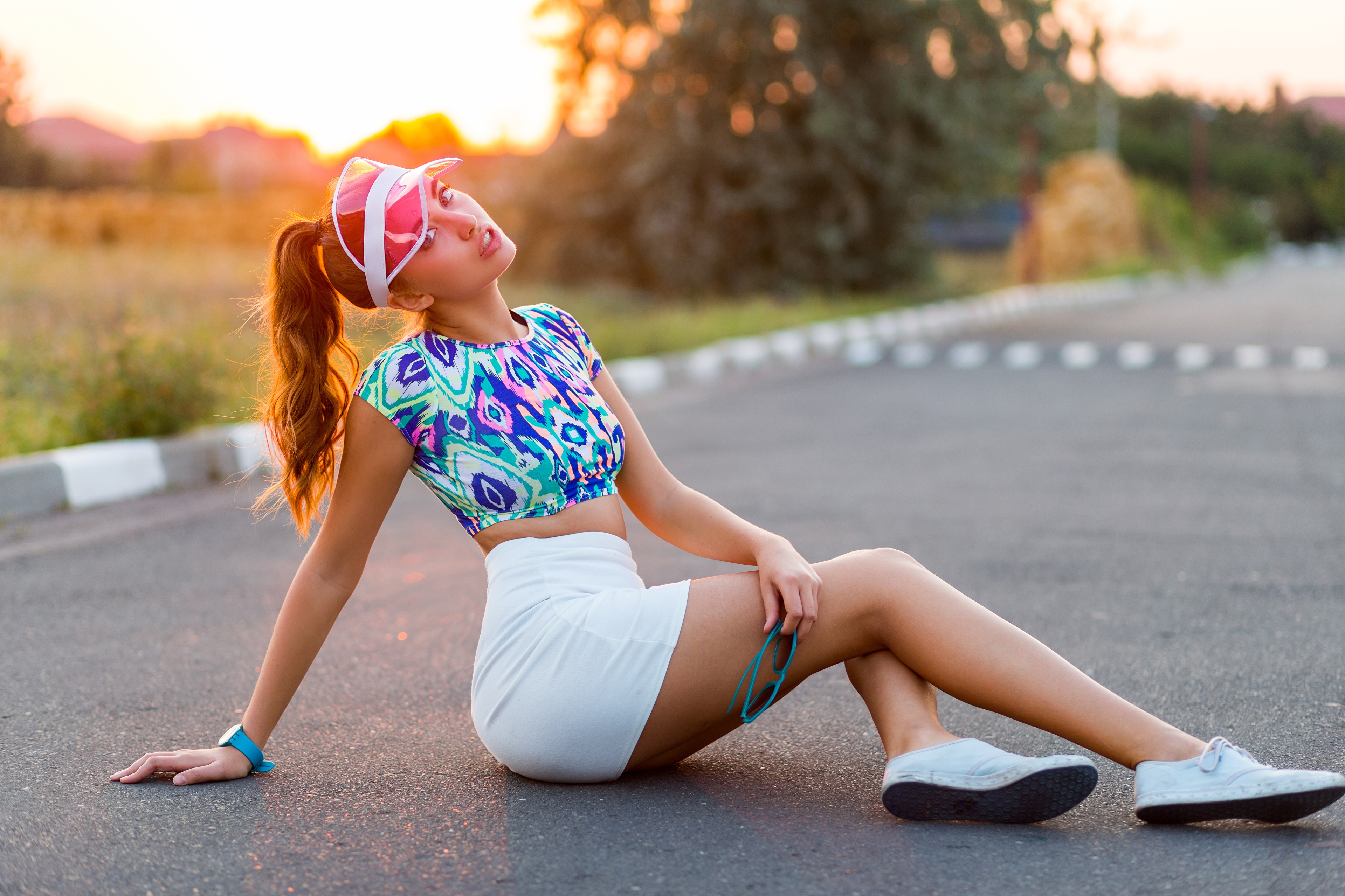 Woman in colorful crop top and white skirt sitting on asphalt HD Wallpaper