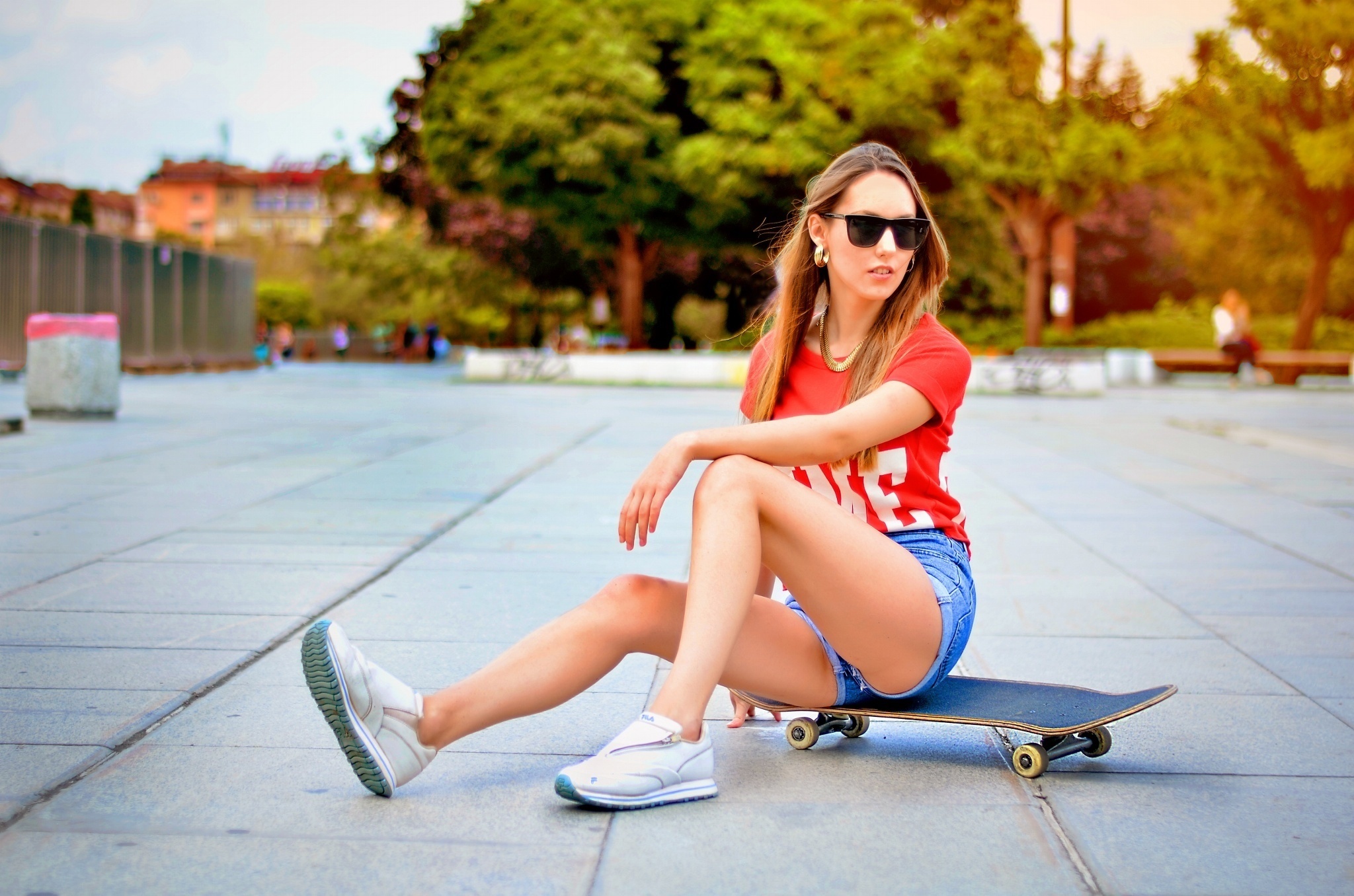 Woman in red t-shirt and shorts sitting on a skateboard HD Wallpaper