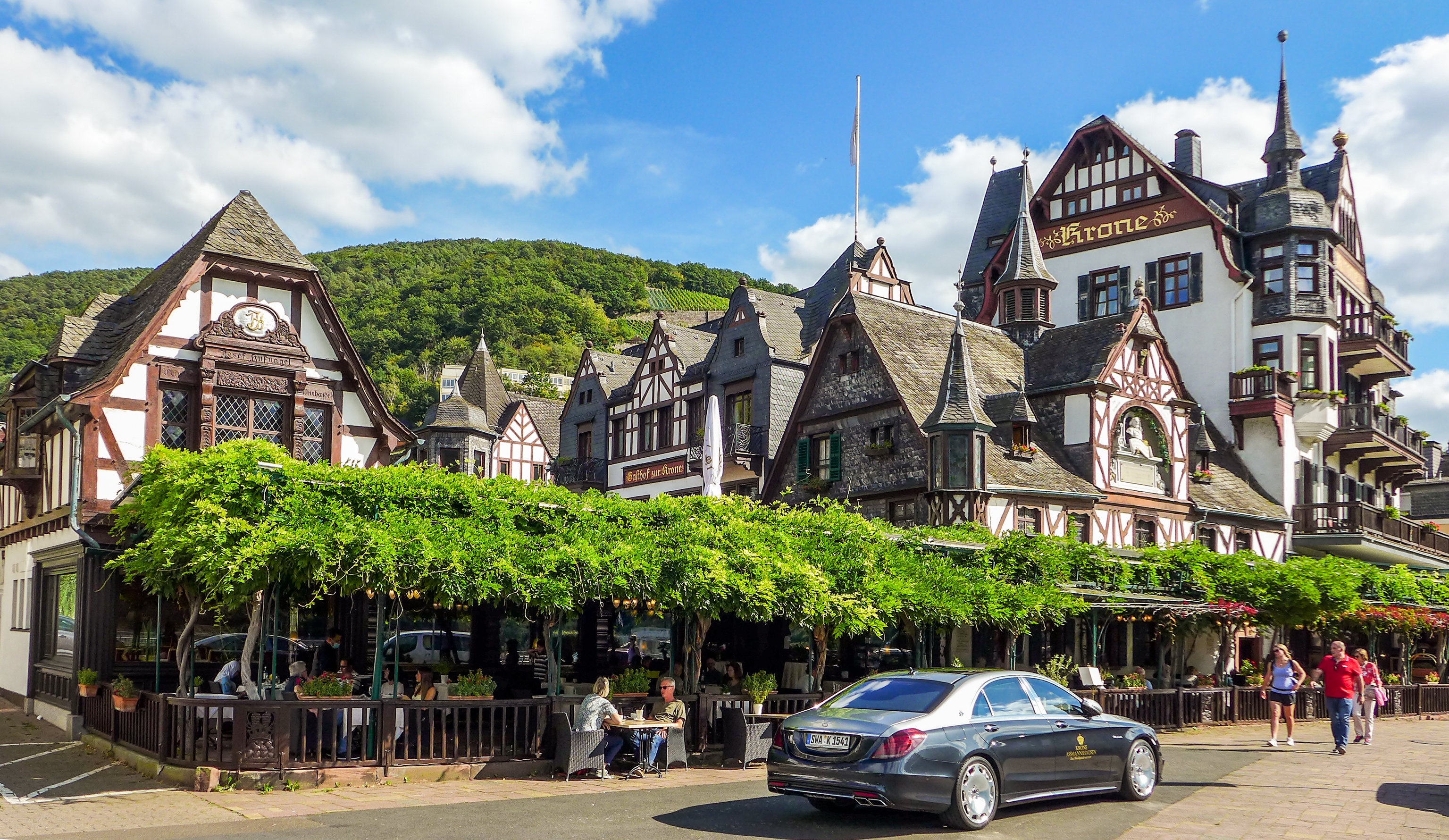 Half-timbered buildings with outdoor seating and a car HD Wallpaper