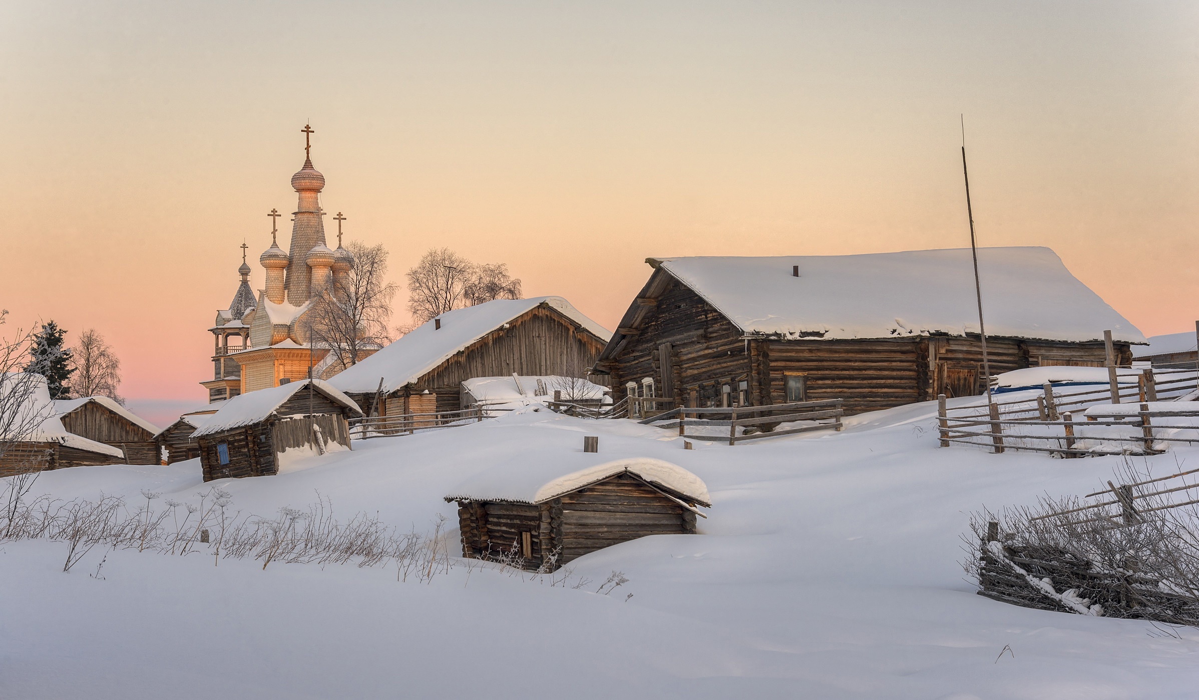 Wooden church and houses in a snowy Russian village at sunset HD Wallpaper