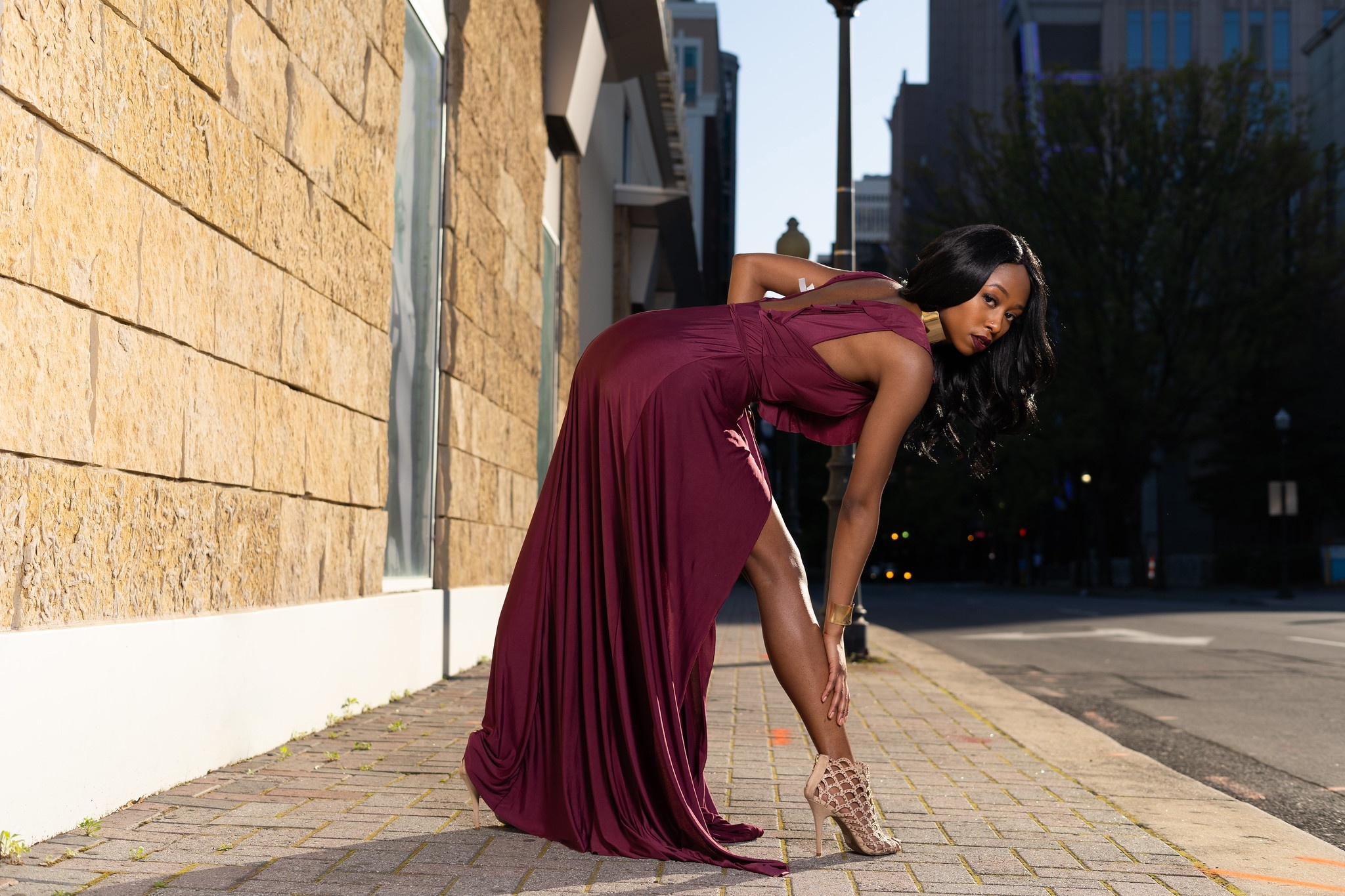 Woman in a maroon dress posing on a sidewalk HD Wallpaper
