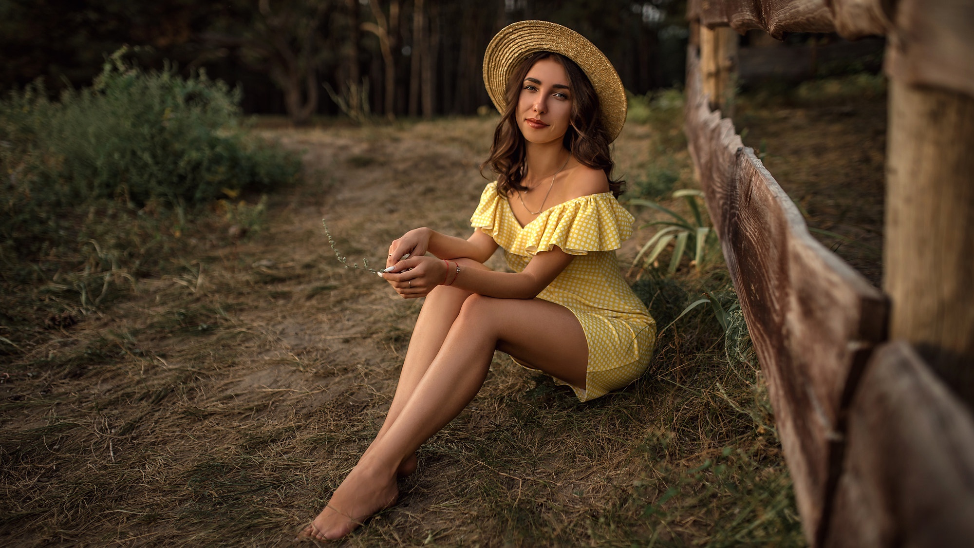 Woman in yellow dress and straw hat sitting by a fence HD Wallpaper
