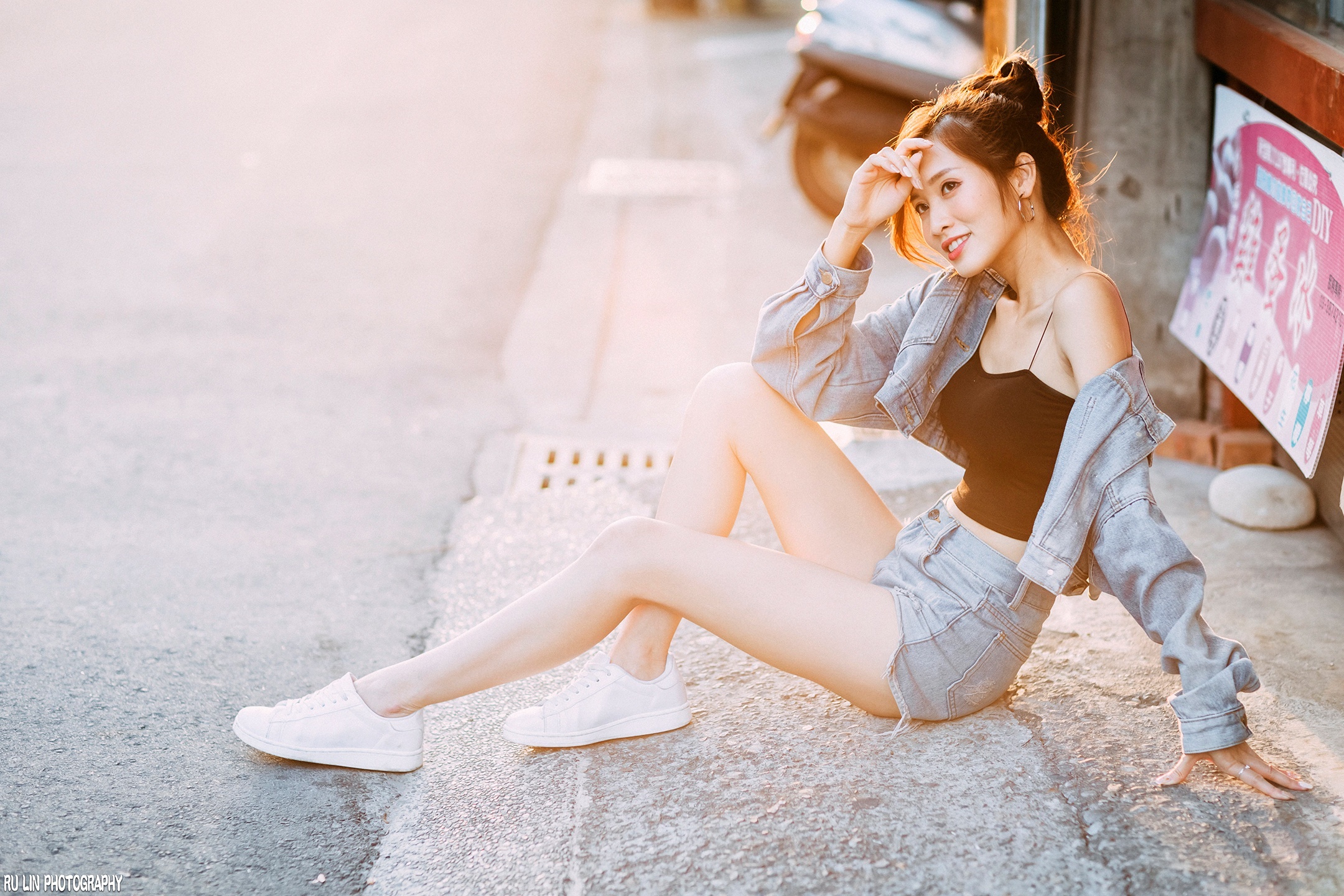 Asian woman in denim shorts and jacket sitting on pavement HD Wallpaper