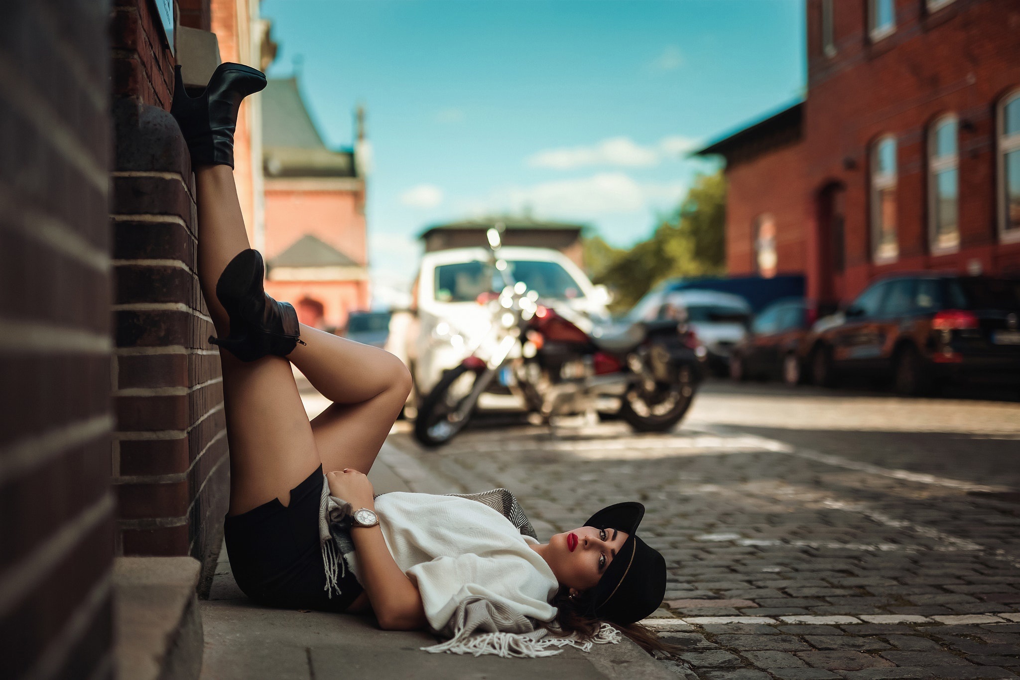 Woman in hat lying on street with legs up HD Wallpaper