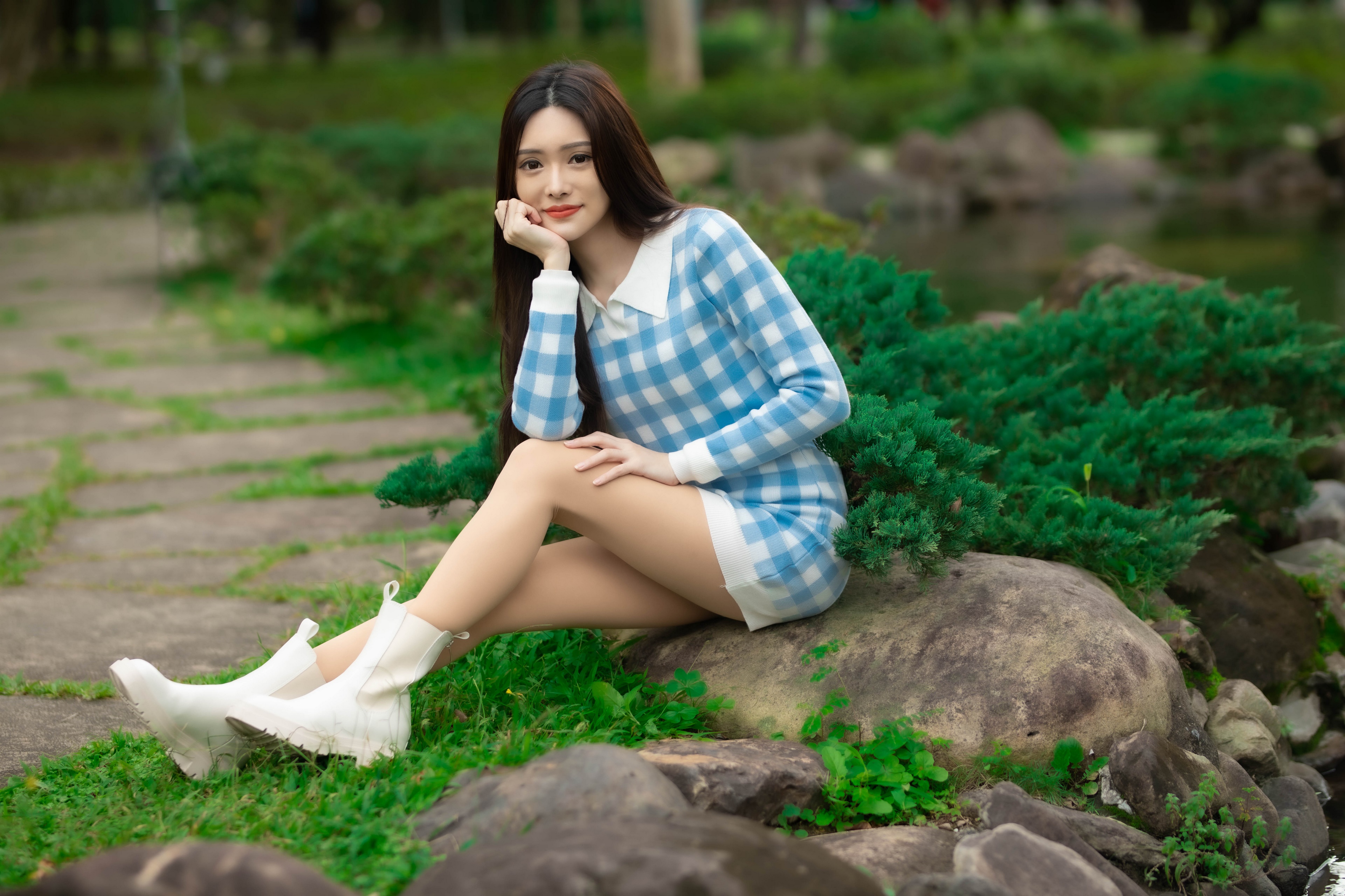 Asian woman sitting on rocks by a pond HD Wallpaper