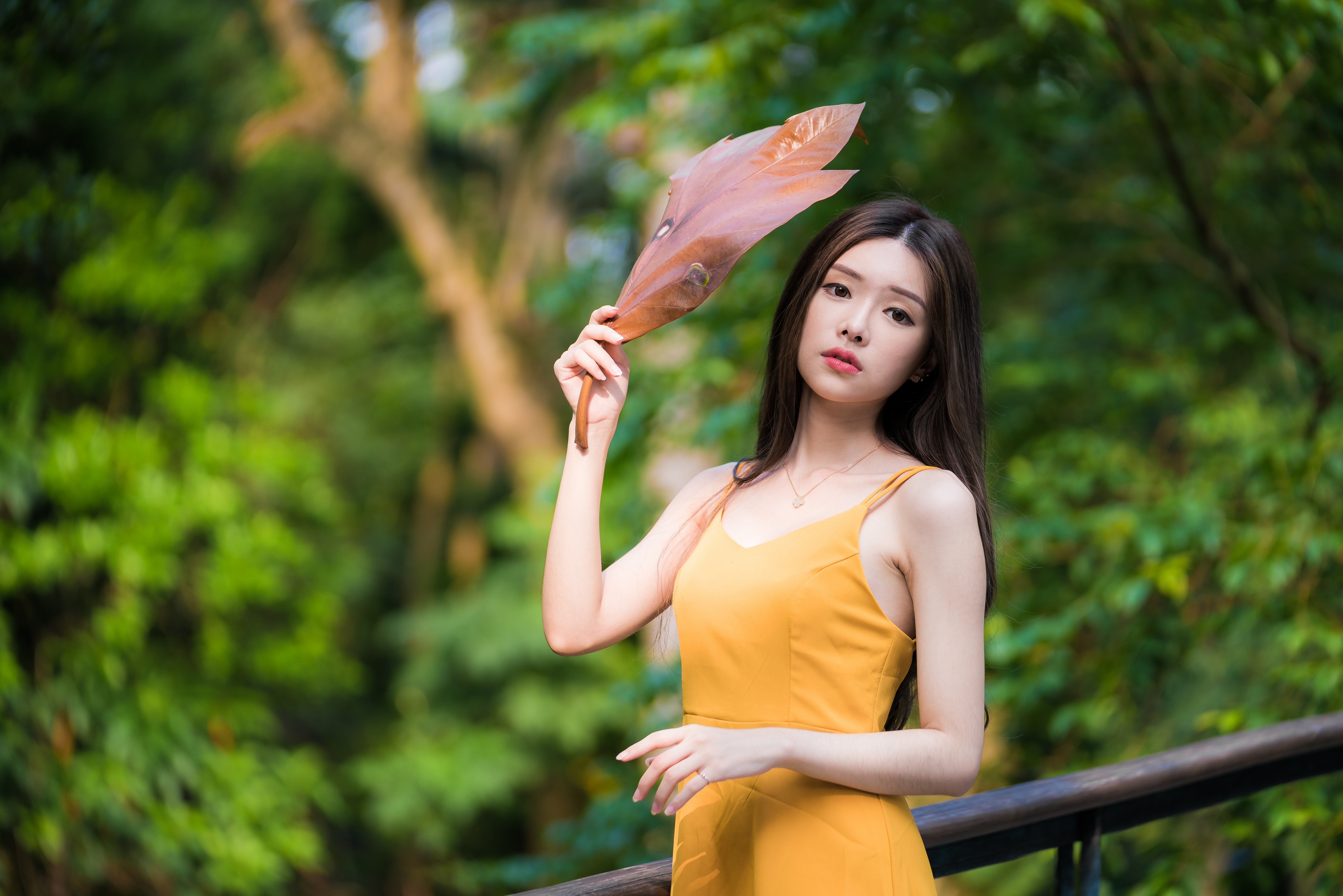 Asian woman in yellow dress holding a leaf HD Wallpaper