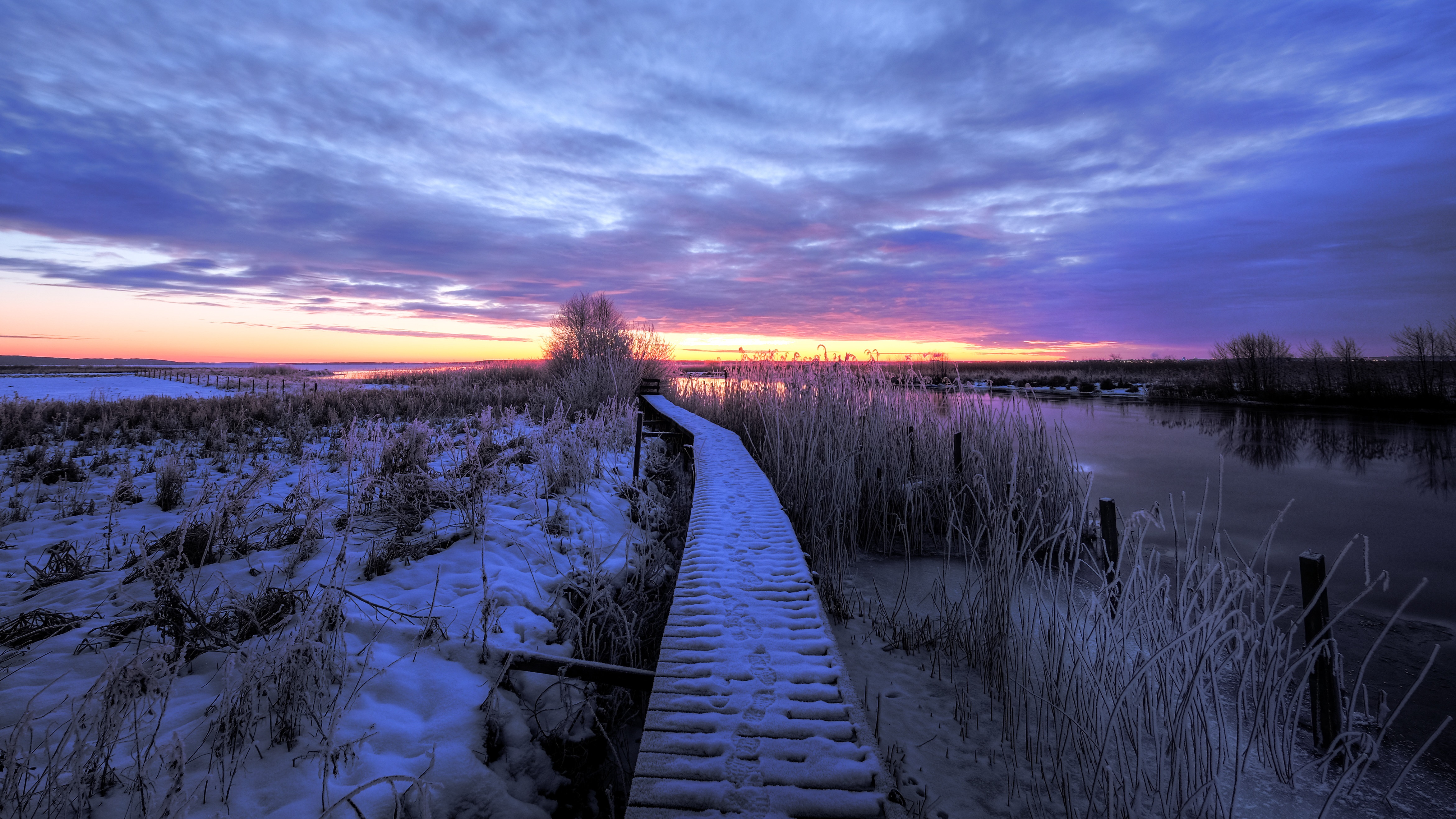 Wooden Boardwalk Through Snowy Landscape at Sunrise in Vreta Kloster, Sweden HD Wallpaper