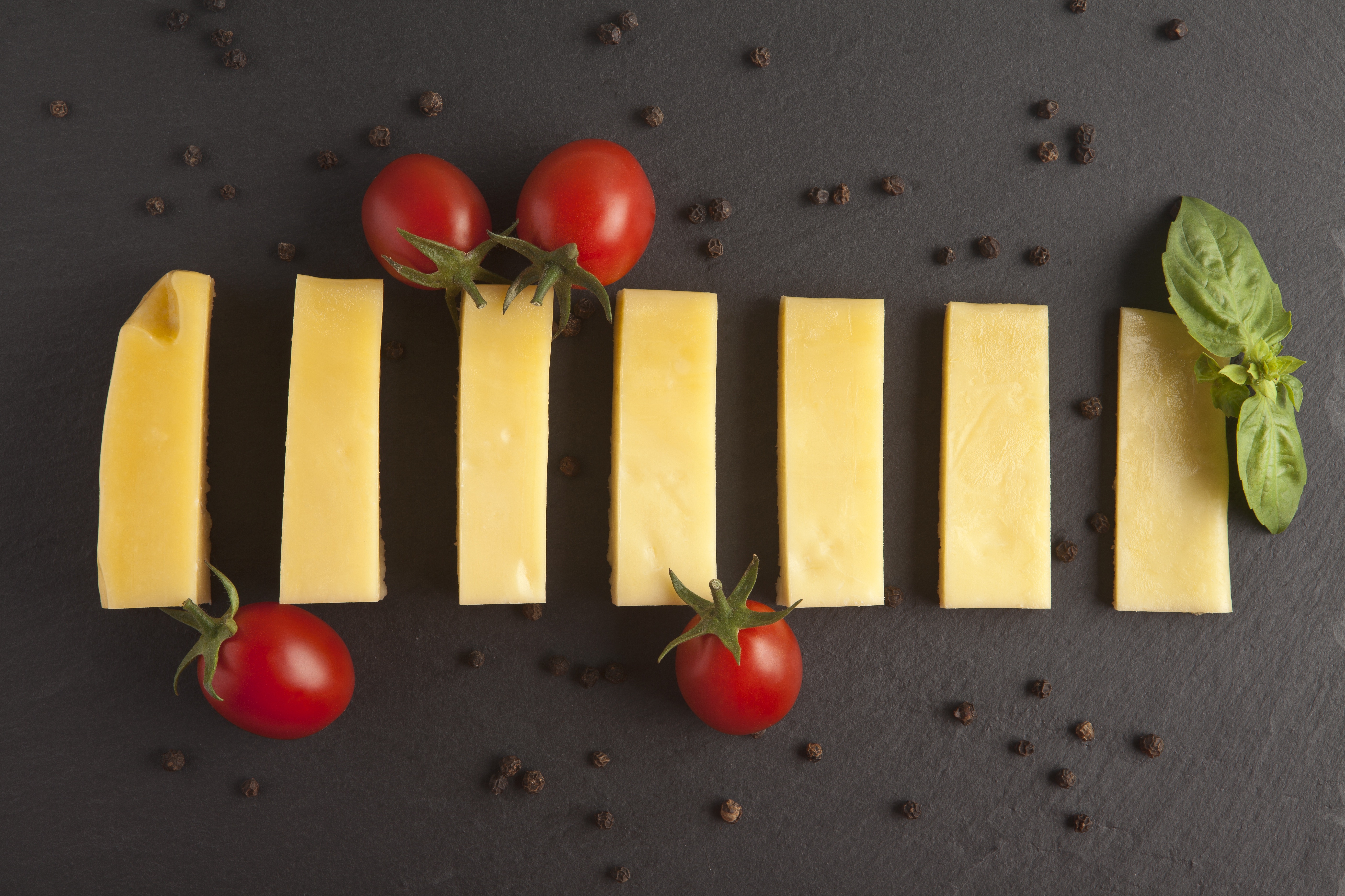 Sliced cheese with tomatoes and basil on black background HD Wallpaper