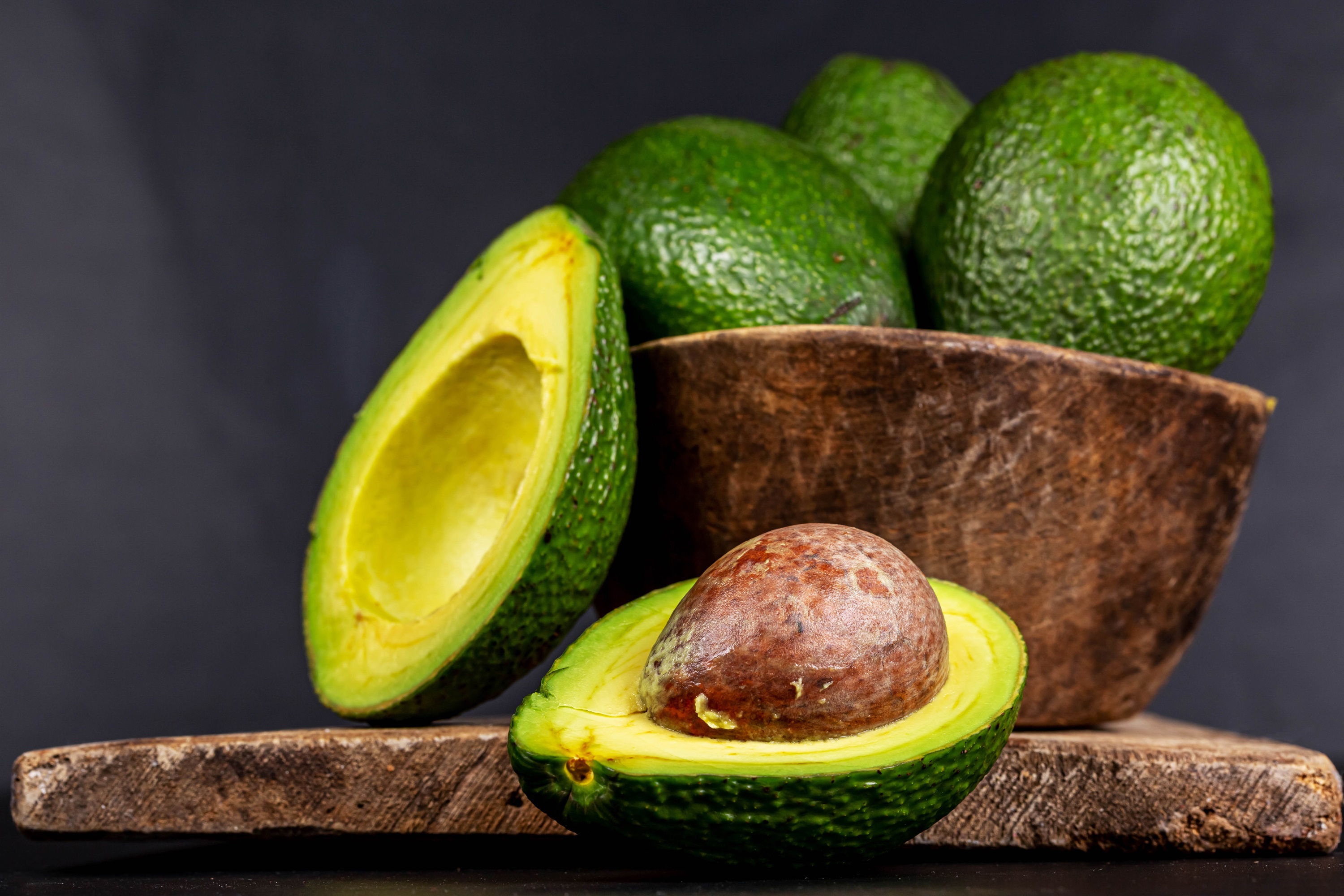 Avocado halves and whole avocados in a bowl HD Wallpaper